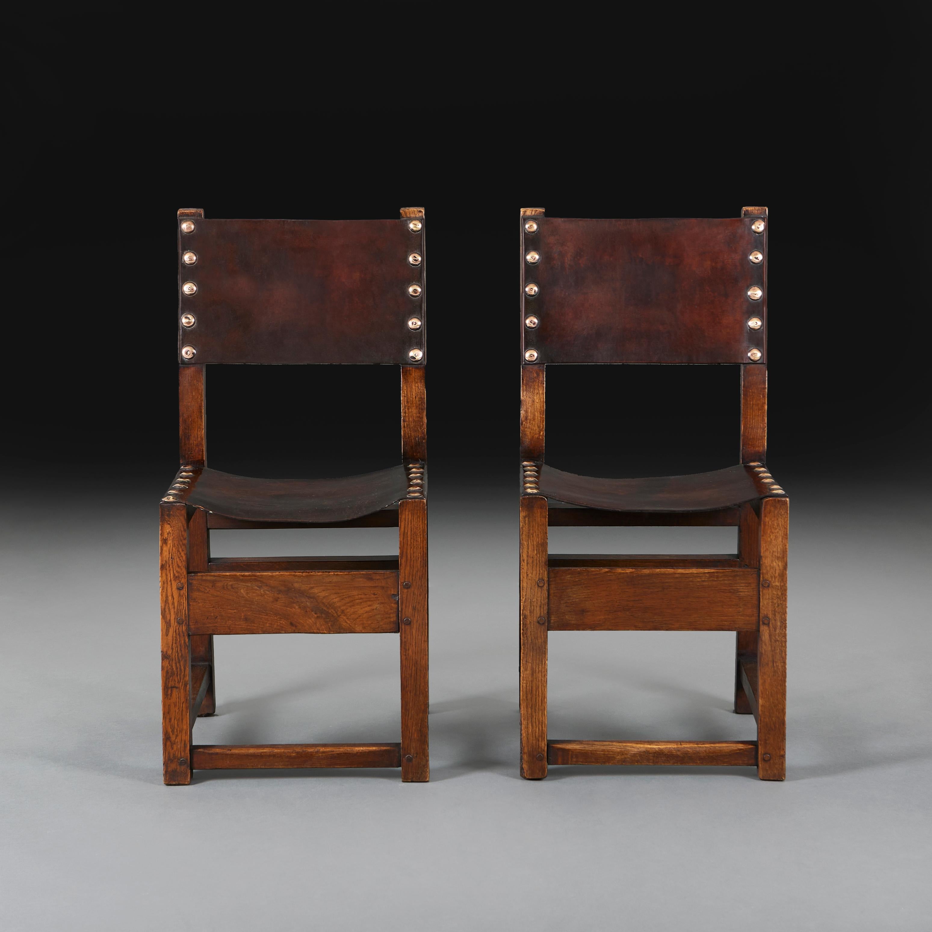 Paire de chaises de salle espagnoles en chêne et cuir de la fin du XIXe siècle, avec des clous en laiton sur l'assise et le dossier.