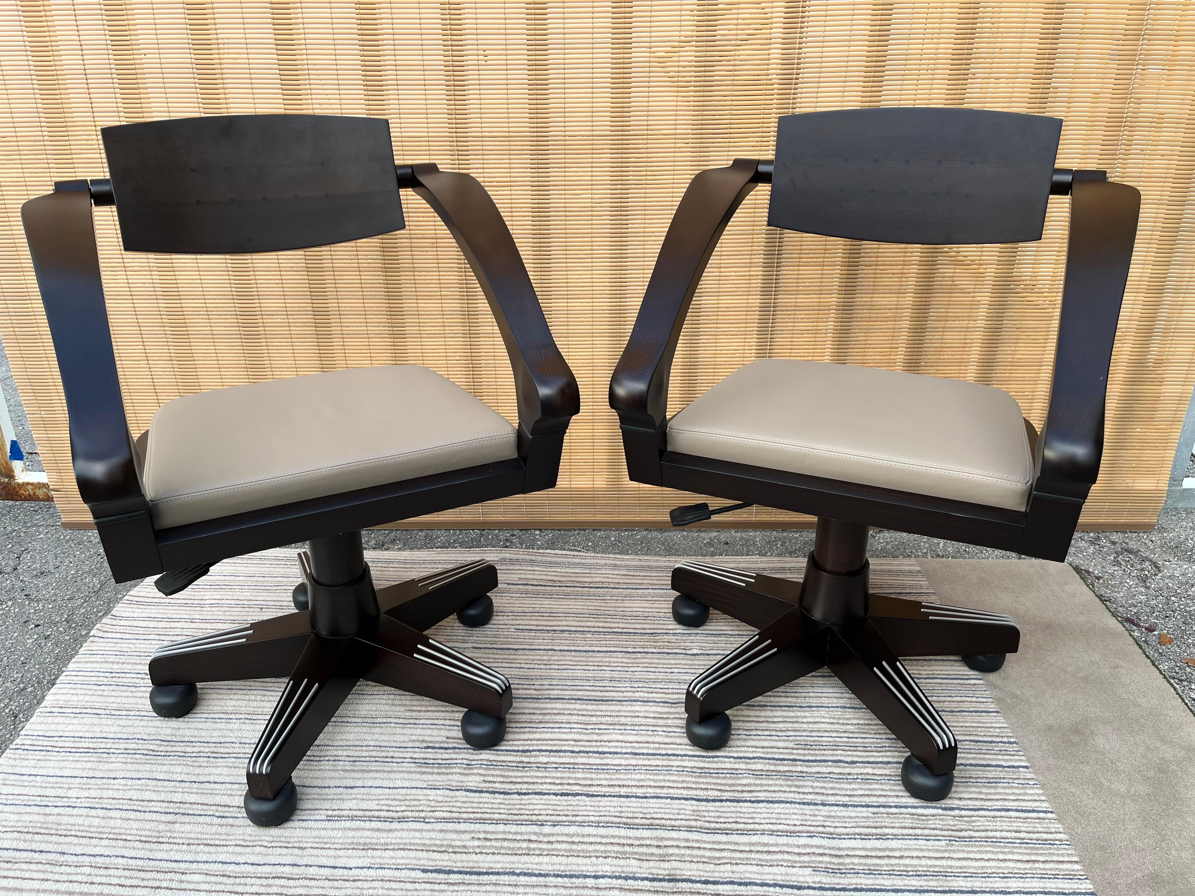 A pair of early 21st century spring swivel armchairs by Massimo Scolari for Giorgetti Italy. 
Feature polished solid beech wood frames, with ebony insets in the backrests. The seats are upholstered in leather. The arms and the back are connected to