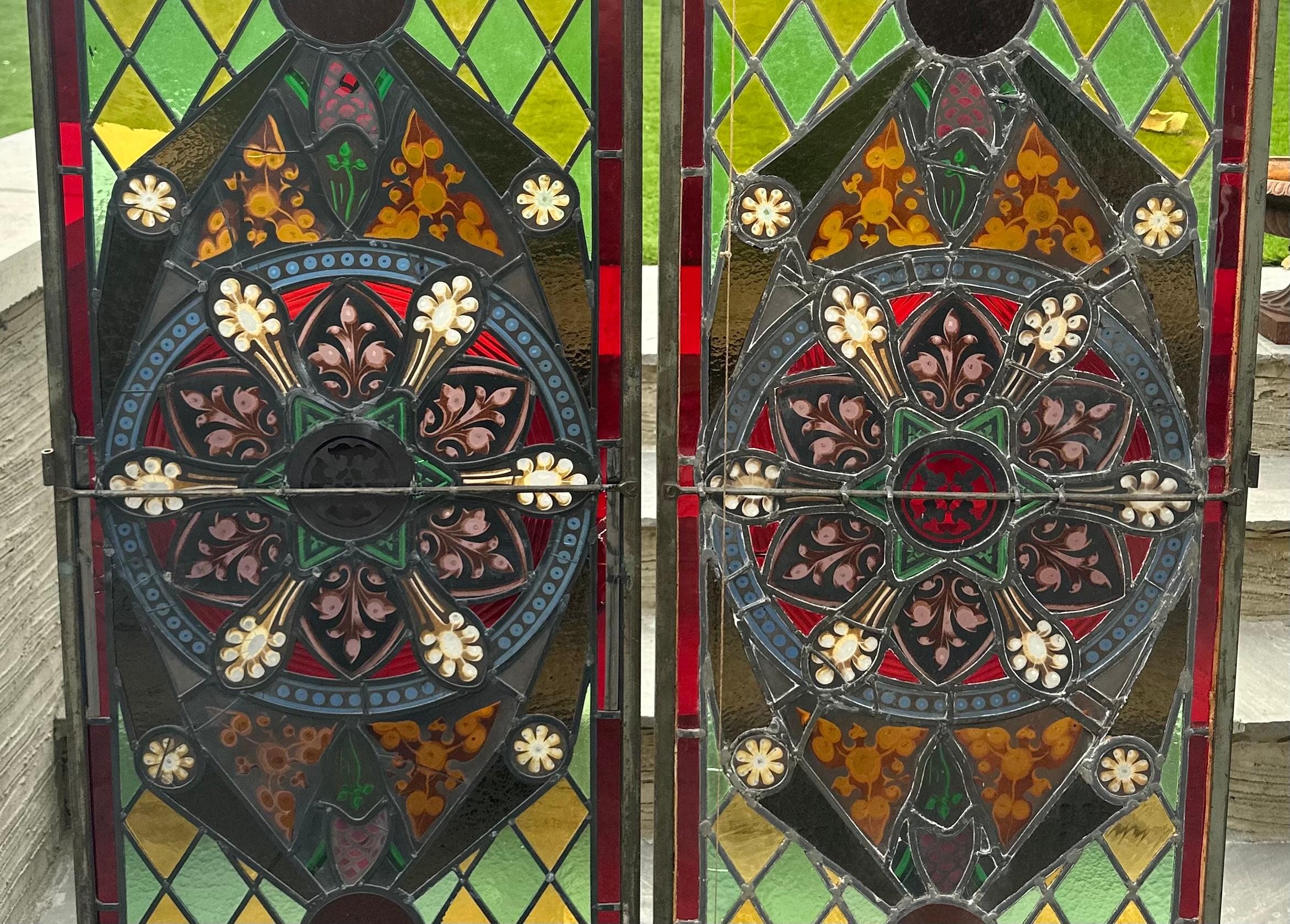 A fine pair of English stain glass doors , originally from an English church , which have been converted into doors in the 1920’s, with acrylic metal frames running around the panels . 
A small panel has come out the bottom right side door , which