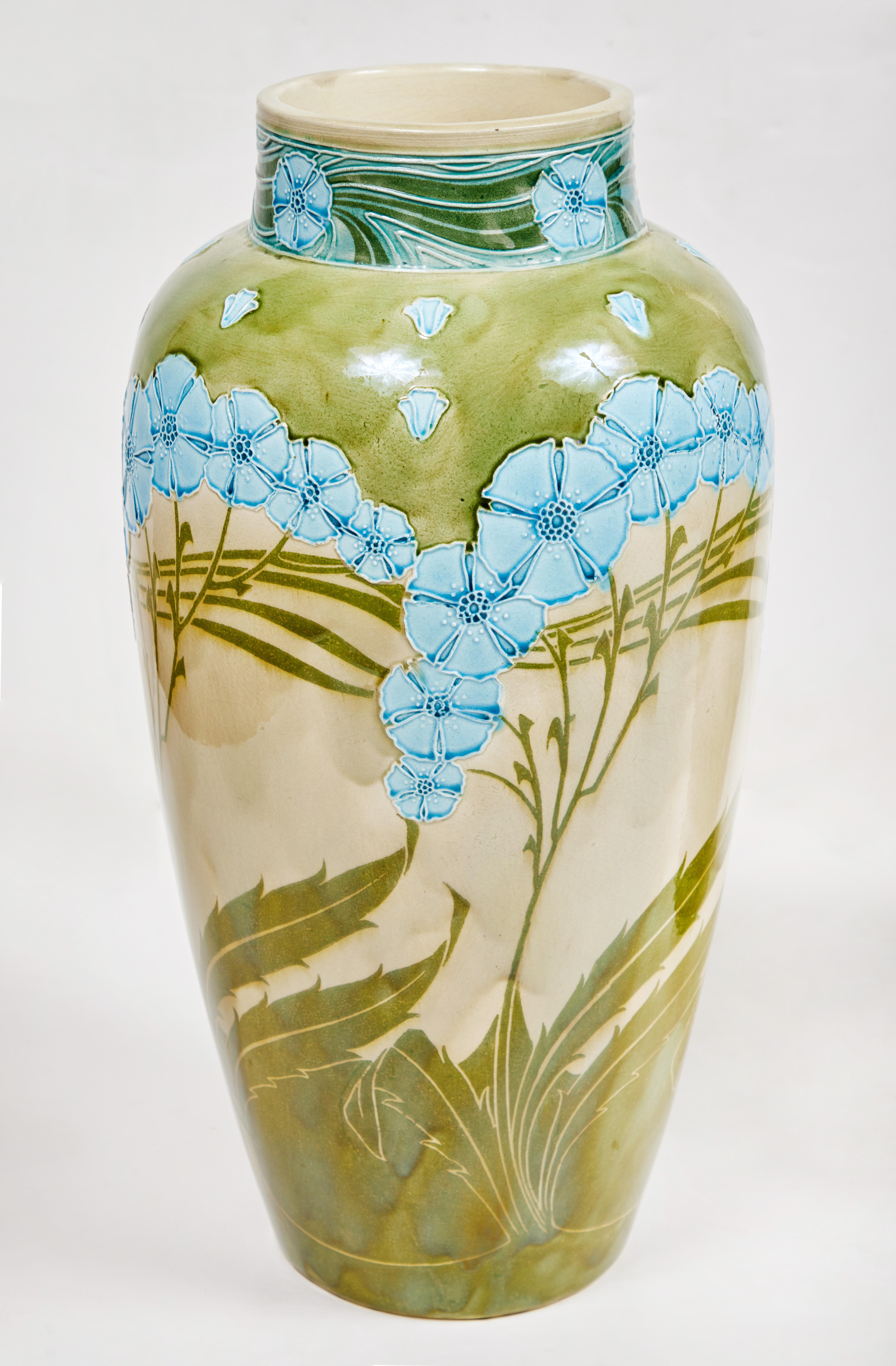 A striking, rare pair of large marked, Minton, Secessionist style, majolica glazed vases with a celadon ground and sprays of Robin's egg blue flowers amidst swaying leaves. Designed by by Léon Solon and John Wadsworth, who drew inspiration from both
