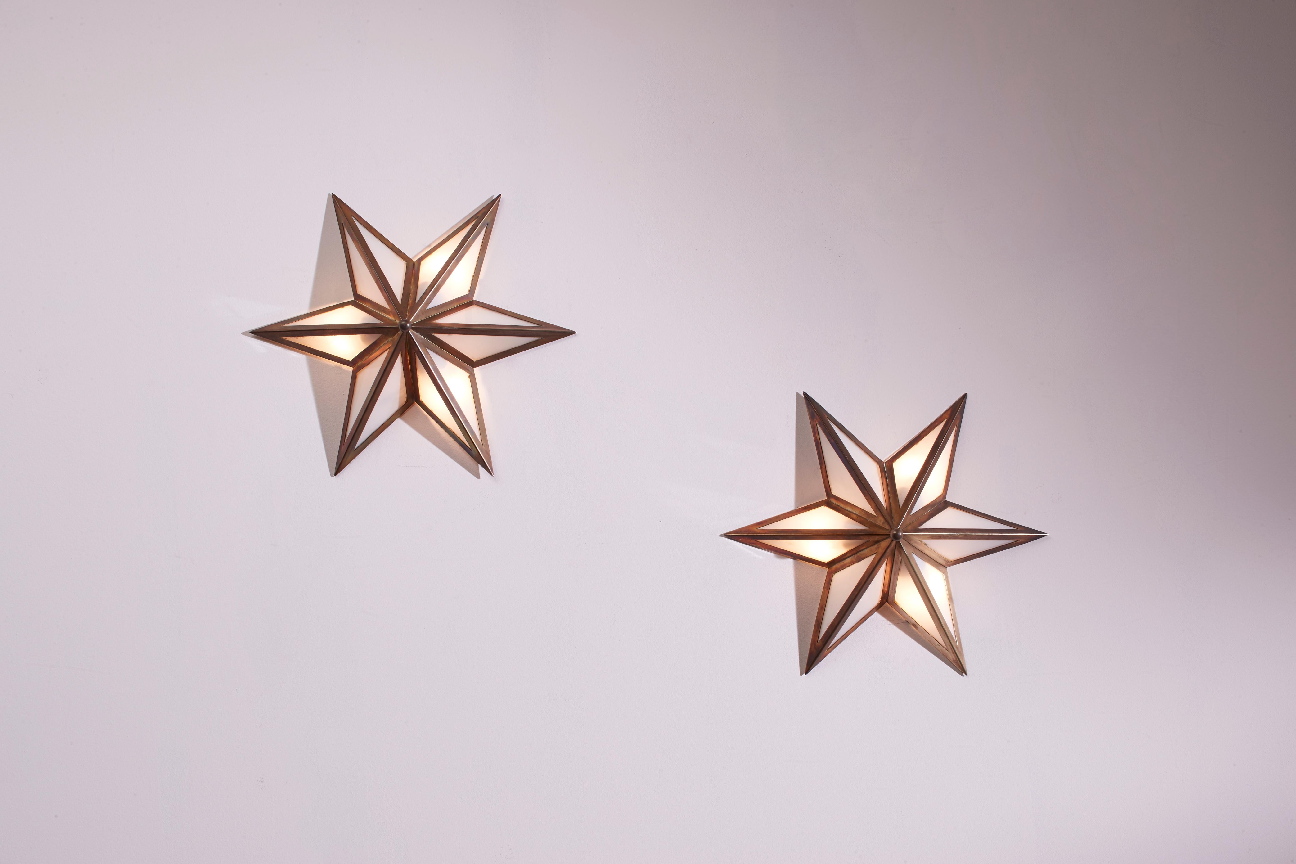 A pair of star-shaped wall sconces, made of brass and glass, represents an authentic example of Italian craftsmanship from the Sixties.

Thin brass profiles frame an opal glass diffuser, shaping a luminous star. This set of wall lamps, two in brass