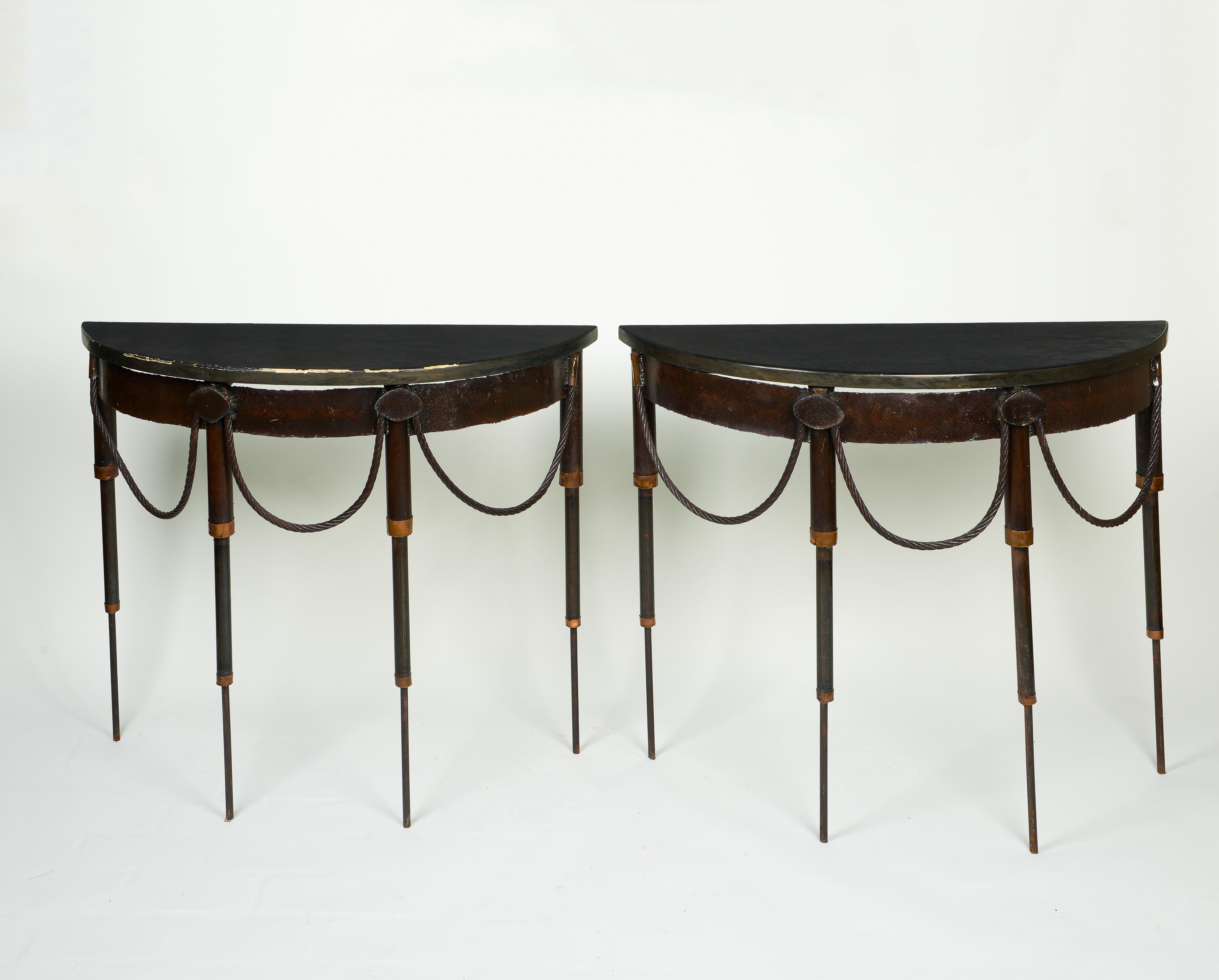 Each with demi-lune-shaped wooden top faux painted to look like black stone; raised on iron rod legs headed by studs festooned with metal rope swags. Unusual and chic.