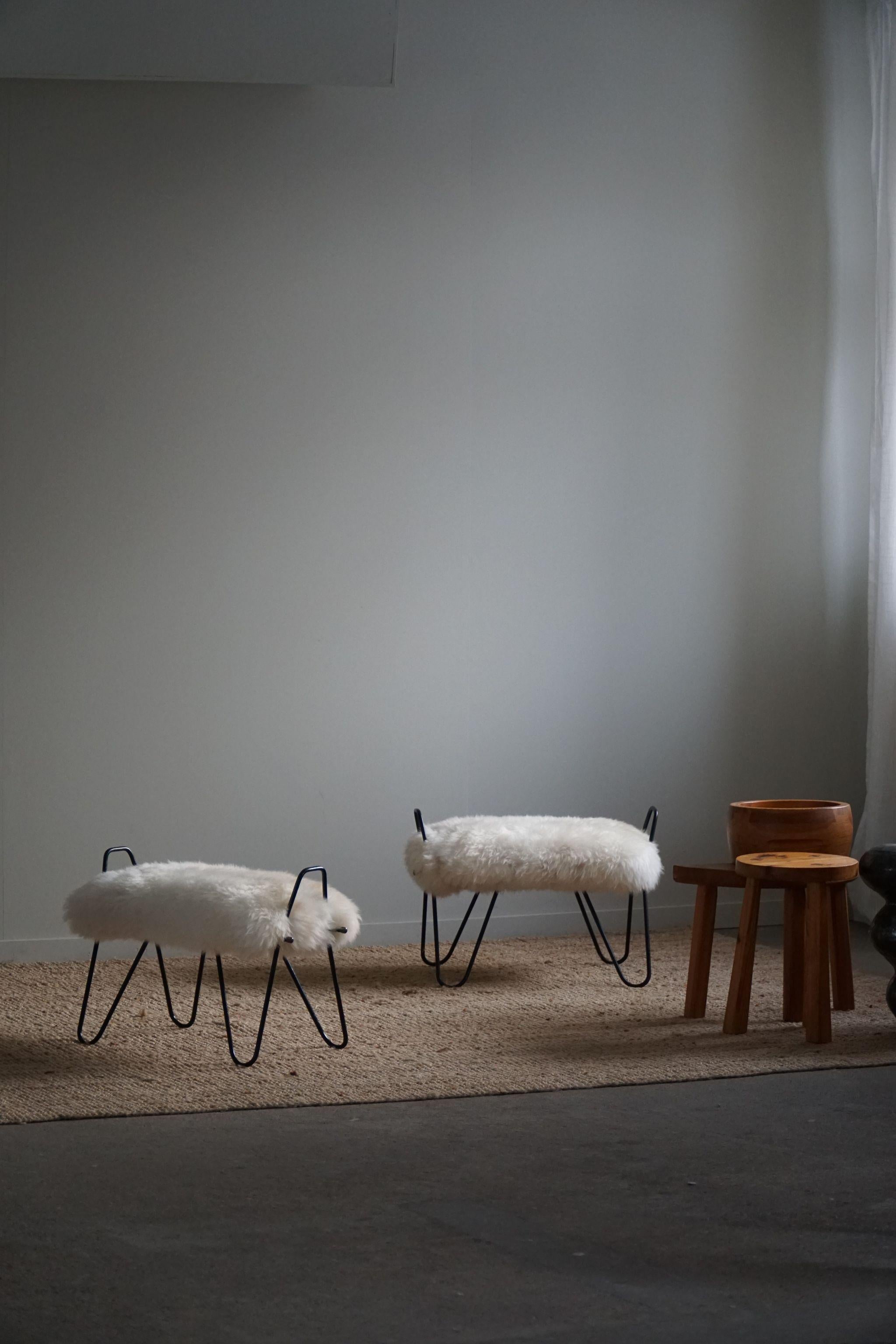 Ein exquisites und seltenes Paar Hocker, hergestellt in Dänemark in den 1960er Jahren. Die Hocker wurden mit einem luxuriösen isländischen Schafsfell neu gepolstert, das der Gesamtästhetik eine weiche und fühlbare Textur verleiht. Die Wolle ist warm
