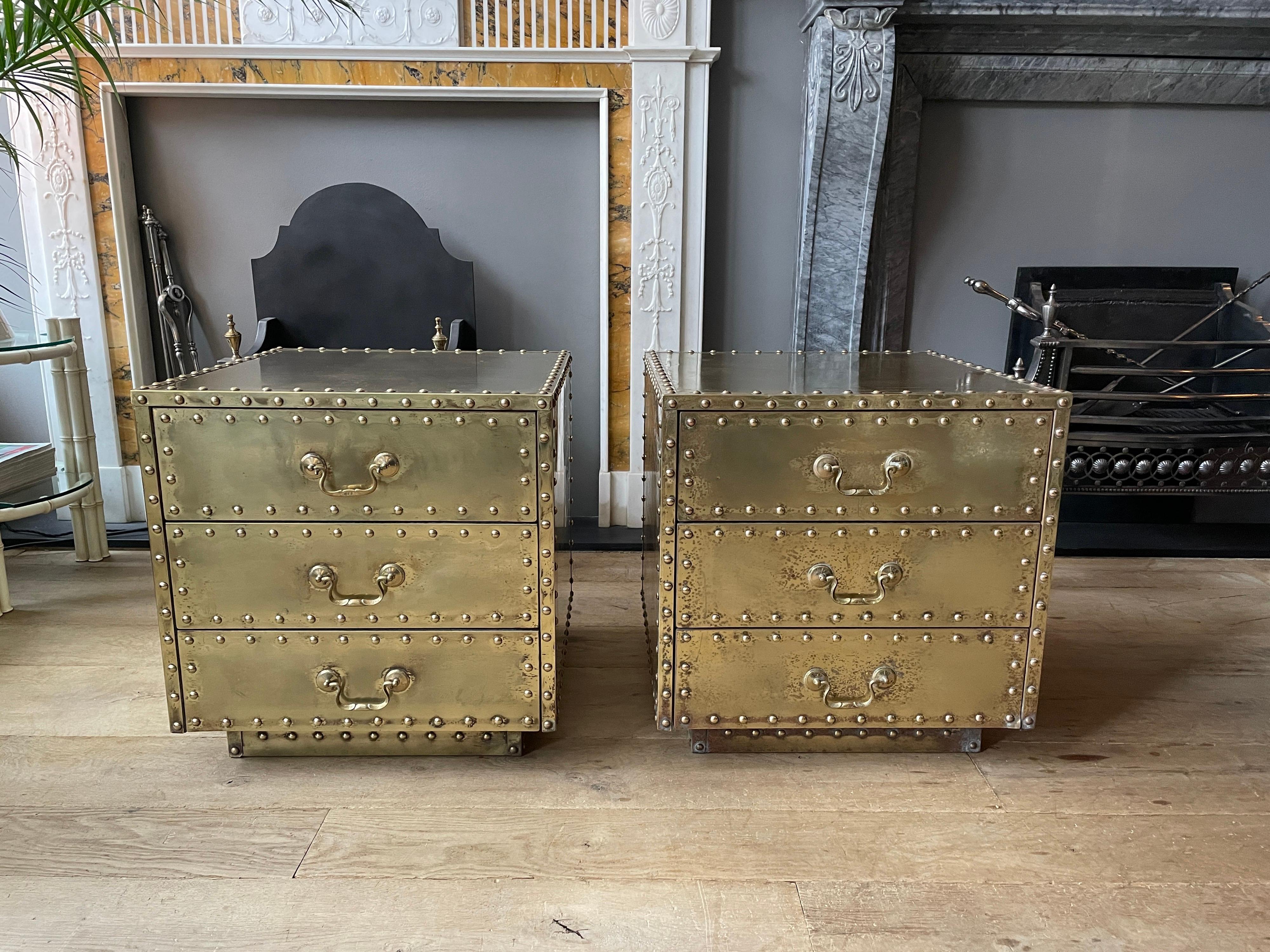 A pair of small chests, bedsides or night stands covered in brass by Sarreid Spain. A bank of three drawers with studded edge and studded plinth, original aged and lightly distressed patina. 

Circa 1970 Spain.