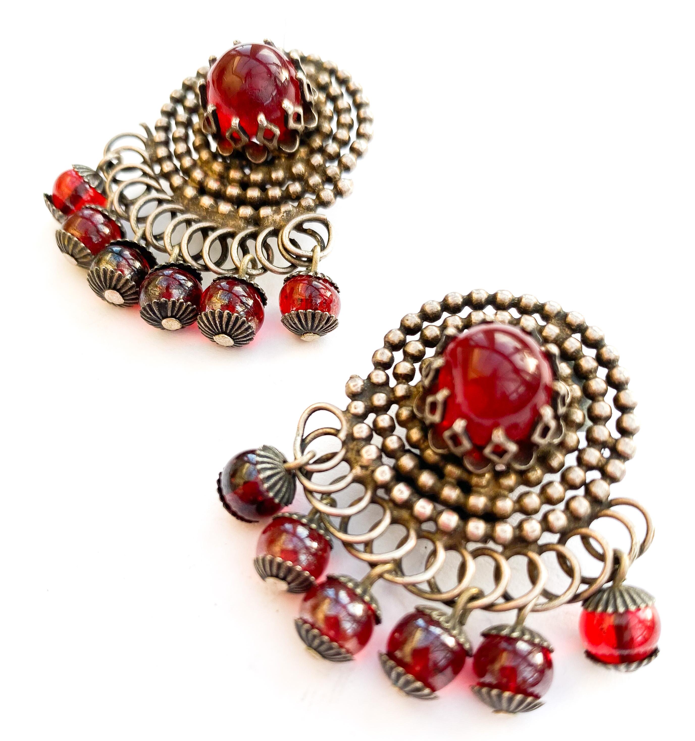 With a slightly ethic style yet clearly exuding French style, these large earrings have the look of antique cut steel, as made from a dark silvered metal, on swirls, and set with a single large ruby glass cabuchon in each - with ruby glass beads