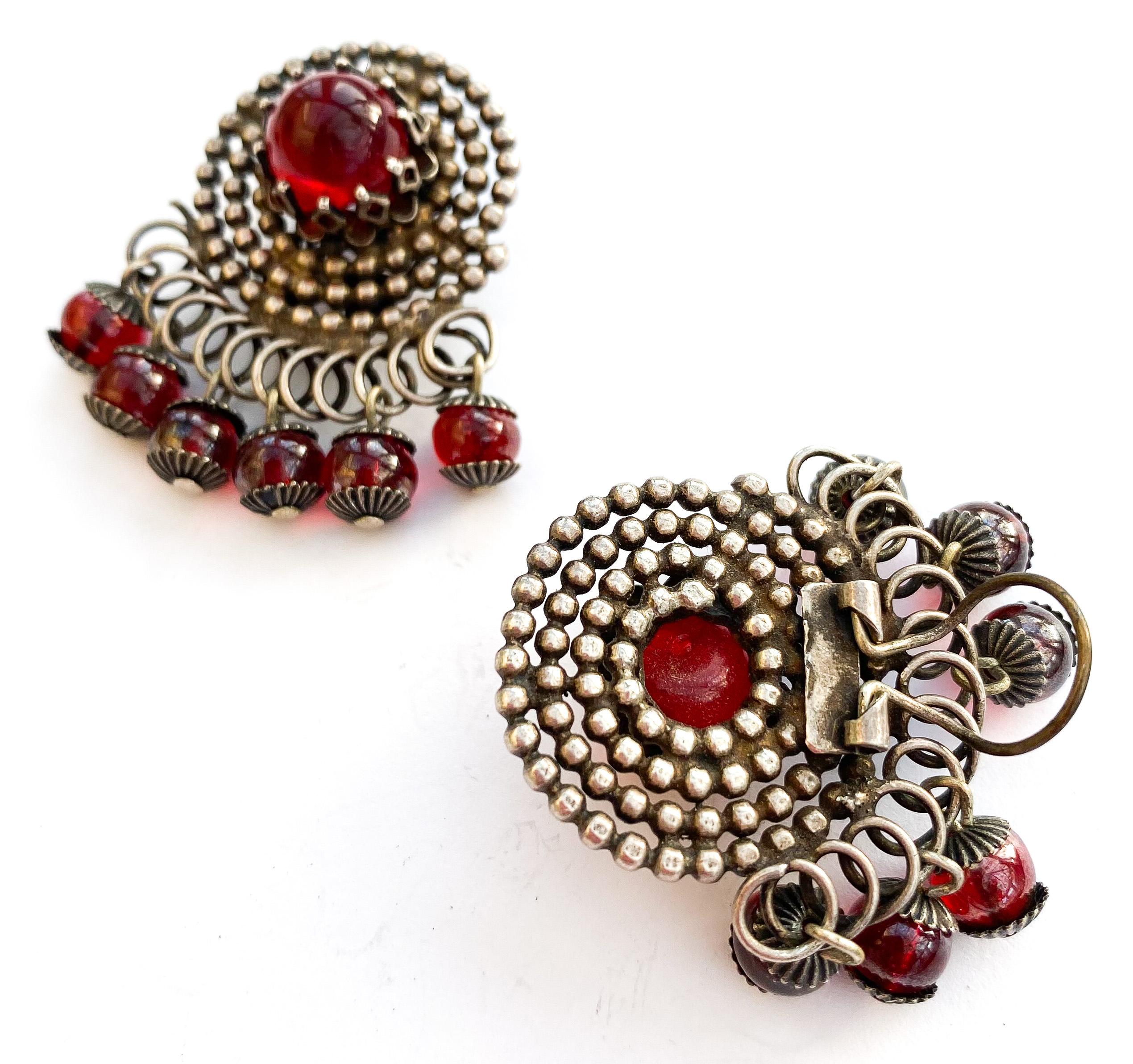 Par de pendientes estilizados de metal plateado y vidrio rojo en forma de 