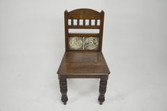 A pair of substantial Gothic Revival oak hall chairs with period tiles