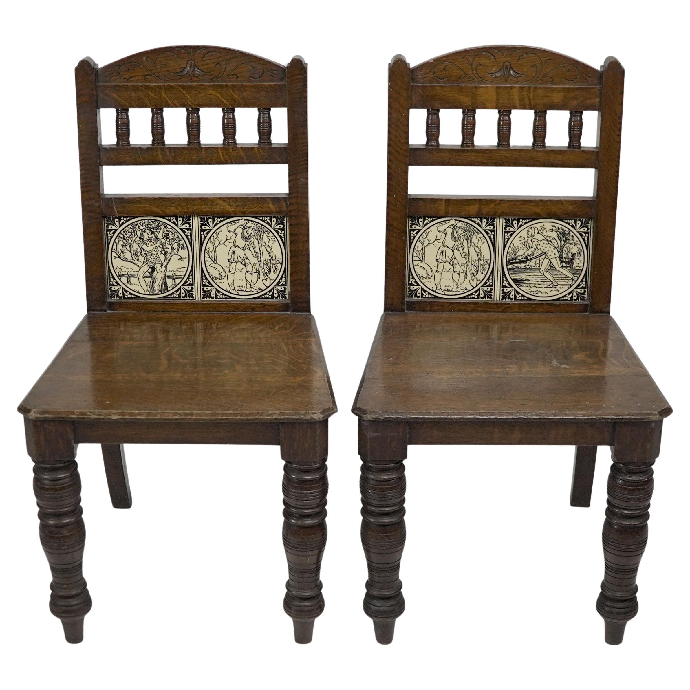 A pair of substantial Gothic Revival oak hall chairs with period tiles