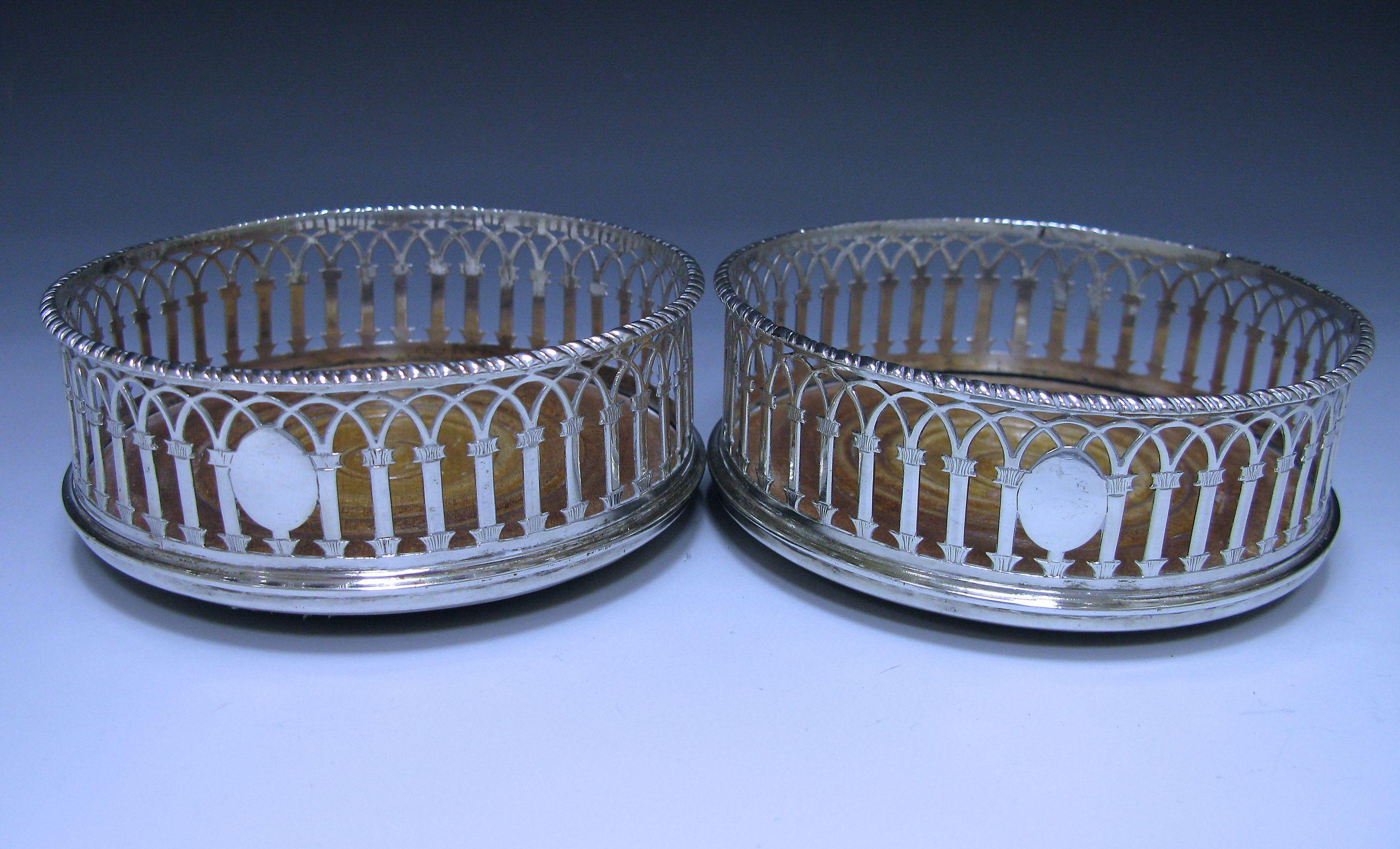 A pair of superb George III antique sterling silver coasters with rope -twist edges, pierced arched shaped borders and turned wooden bases. The pierced borders also contain an oval vacant cartouche. The coasters have green baize to the underside.