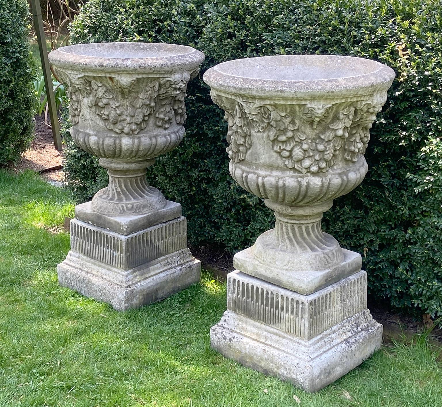 Baroque Pair of Swag and Mask Composition Stone Urns on Decorative Pedestals