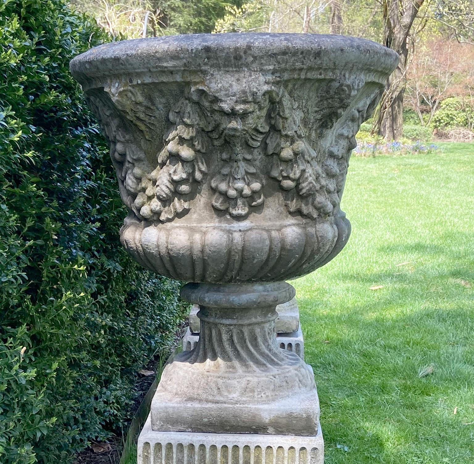 Pair of Swag and Mask Composition Stone Urns on Decorative Pedestals In Good Condition In Katonah, NY