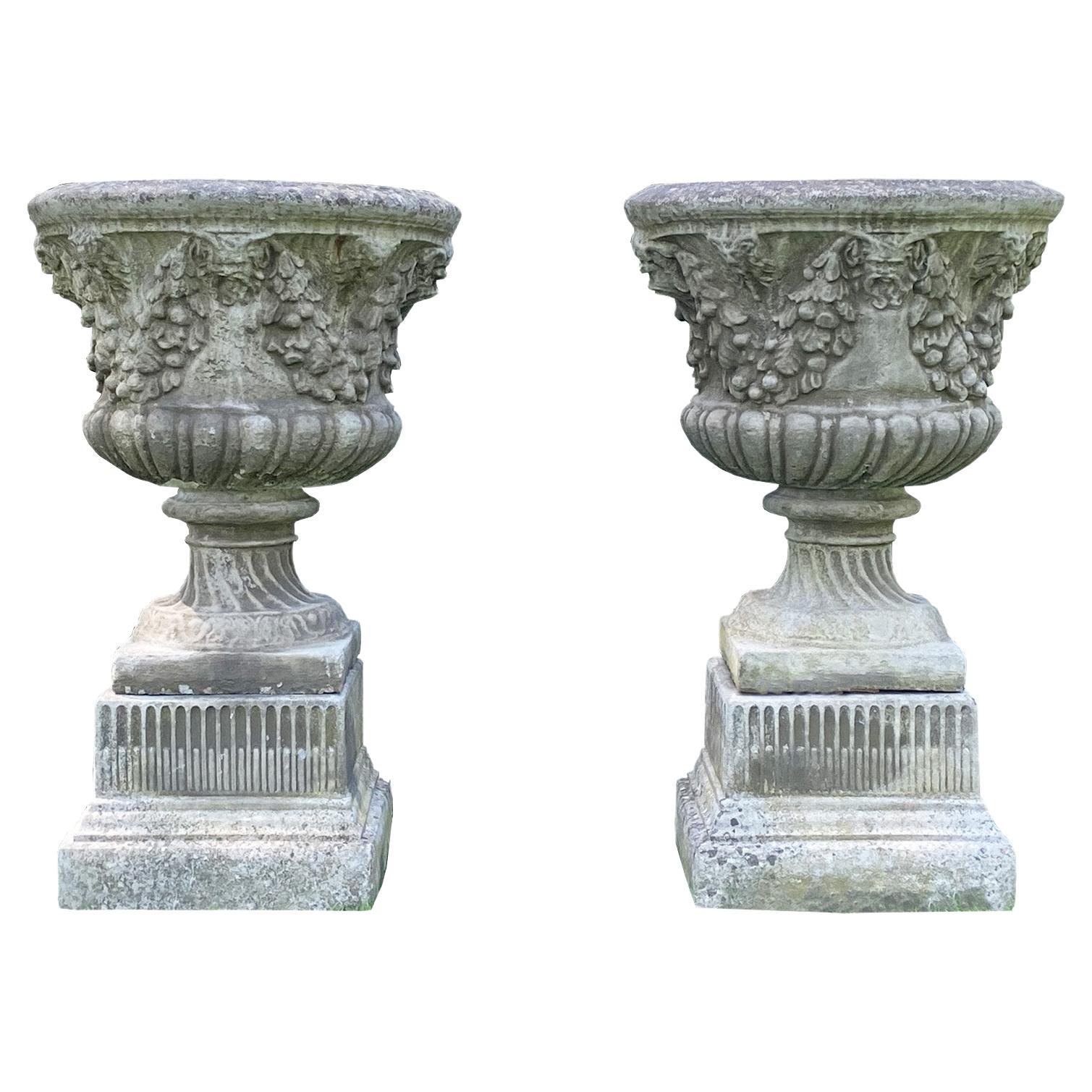 Pair of Swag and Mask Composition Stone Urns on Decorative Pedestals