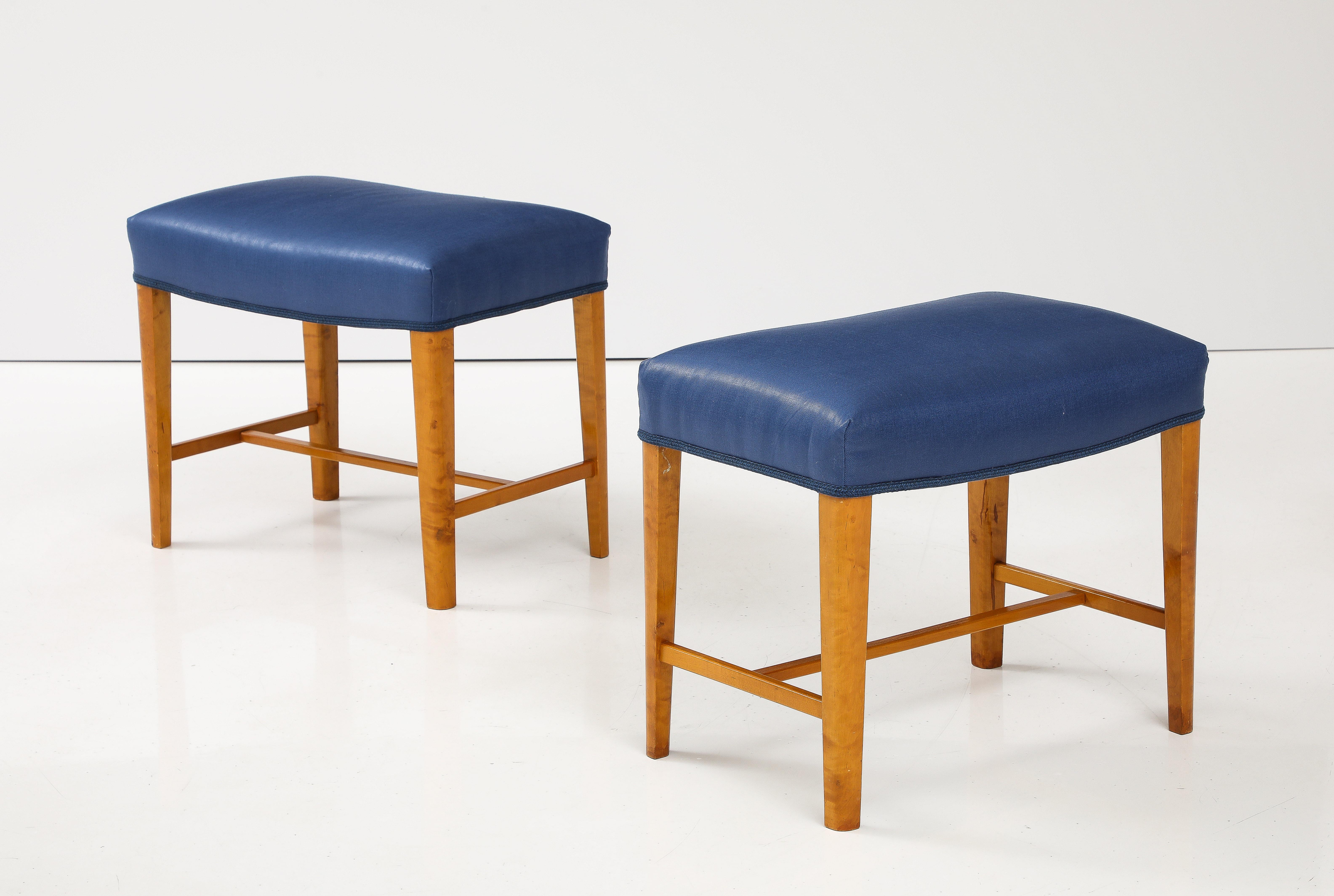A pair of Swedish birch wood stools, Circa 1940s, the upholstered rectangular tops raised of straight legs with a rounded edge and joined by an H-form cross stretcher. Re-covered in Rogers & Goffigon glazed linen.
