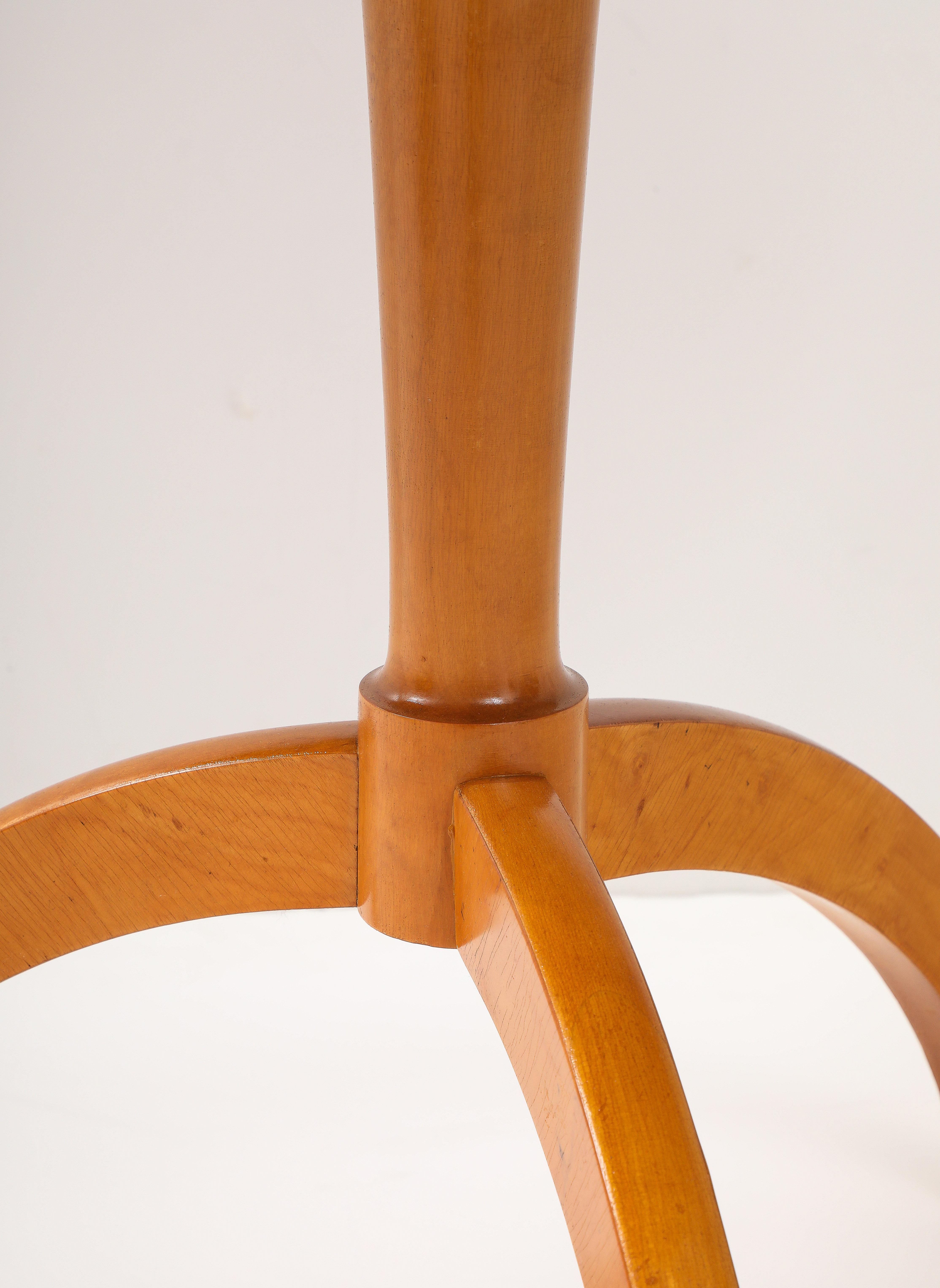 Coppia di tavoli svedesi in legno di betulla, CIRCA ANNI '40, con piani circolari, piedistallo semplice e affusolato sollevato su una base a treppiede ricurva.
