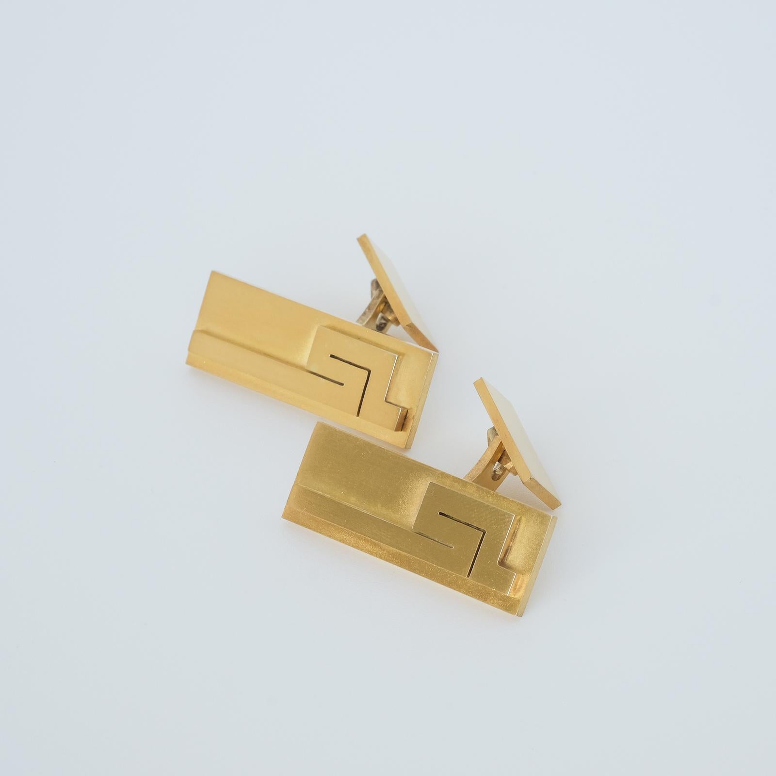 Questi gemelli in argento sterling dorato hanno una forma rettangolare. La superficie è opaca e ornata da un monogramma in rilievo. Il monogramma ricorda un motivo 