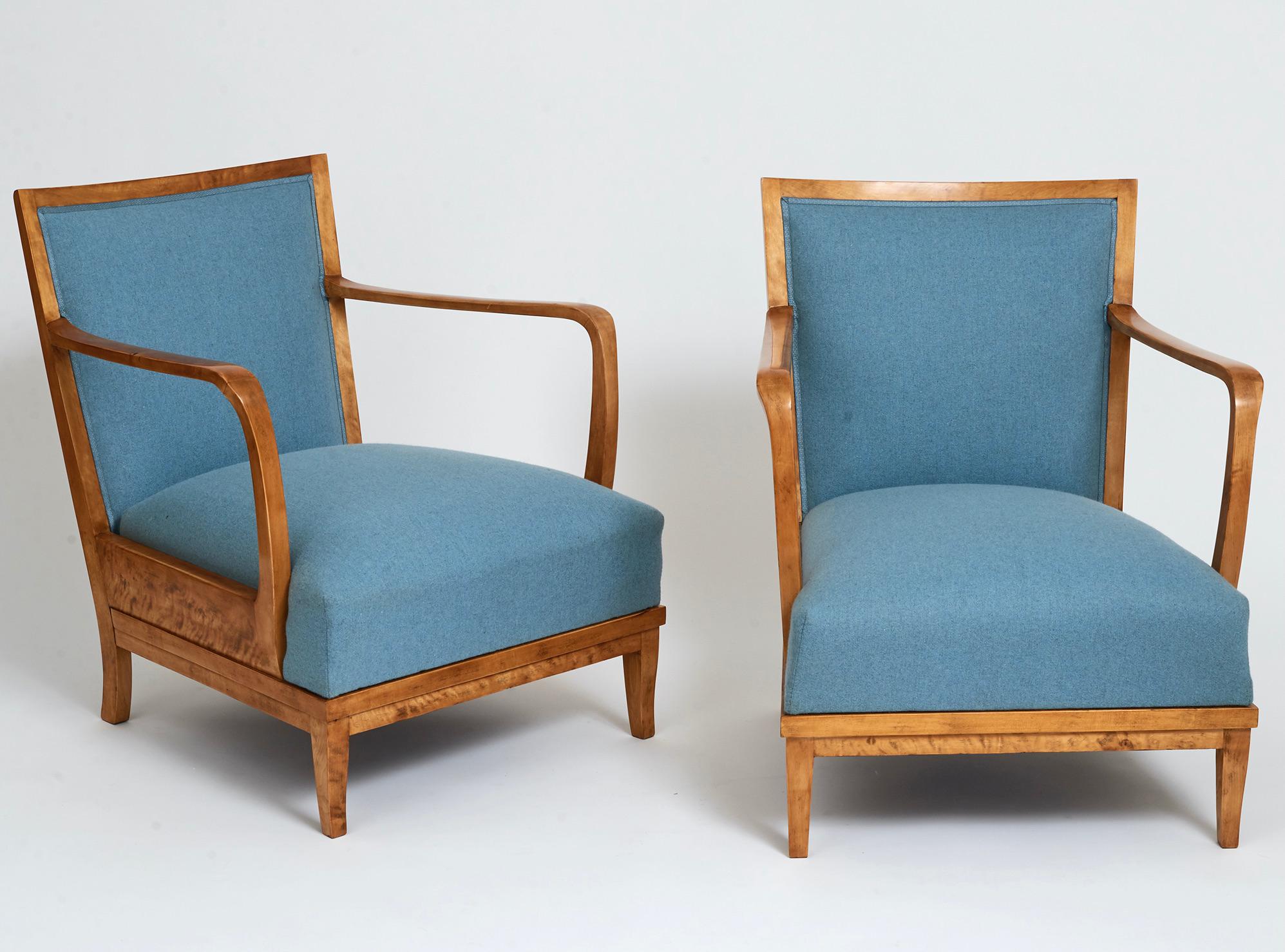 A pair of Swedish grace Birchwood open armchairs, circa 1940s, each with a rectangular upholstered backrest, generous curved open armrests, a drop-in upholstered seat raised on sabre legs.
New blue wool upholstery.

Measures: 58 cm arm