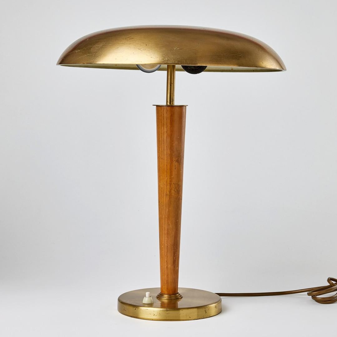 A pair of Swedish Modern table lamps, model 8406, Boréns, dating from the 1940s. Each lamp features a rounded brass base with a push-button switch supporting a tapered elmwood column. The domed brass shade has a patinated surface and is finished