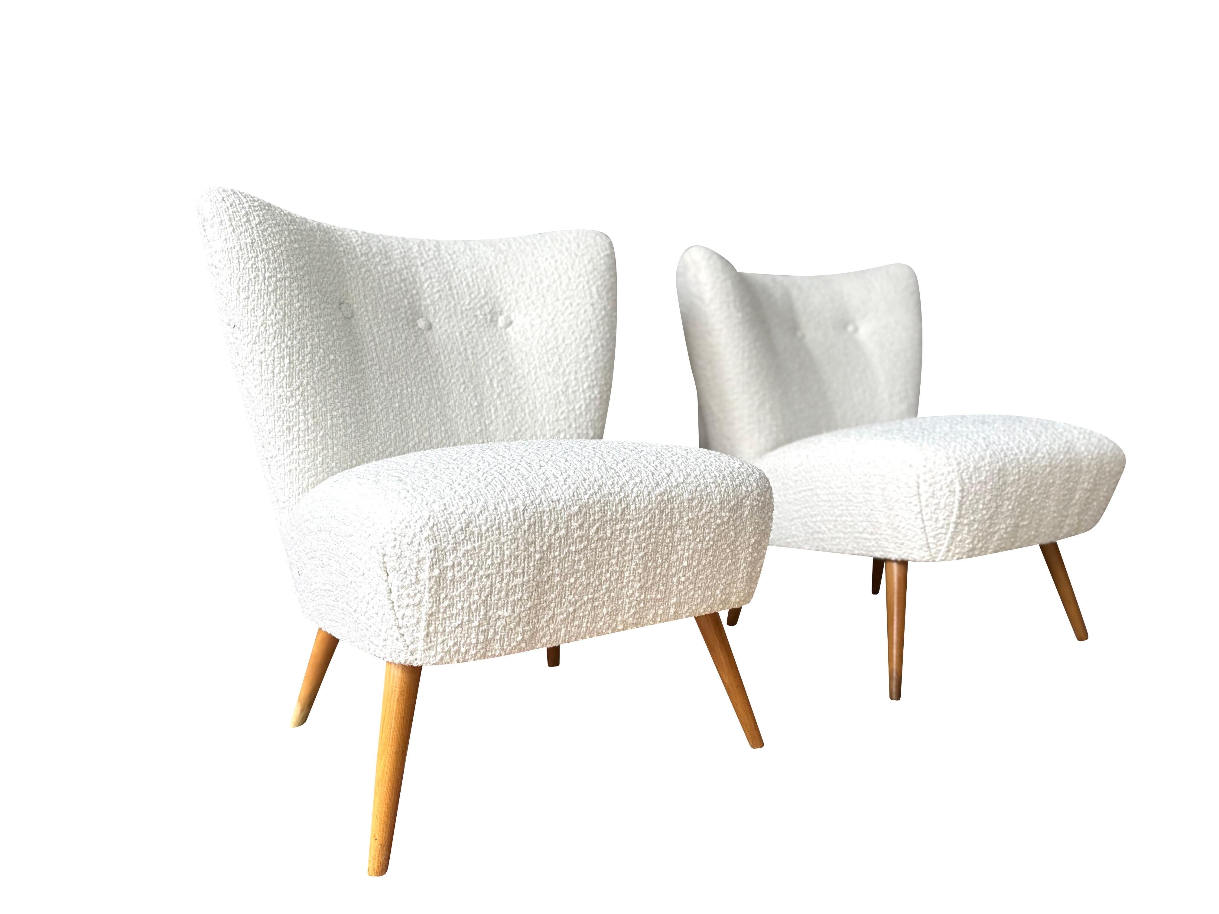 A pair of  Swedish Modern upholstered club chairs from the 1940s. They feature beautifully curved backs and rounded, sprung upholstered seats. The chairs are newly upholstered in off-white bouclé fabric and are very comfortable to sit in.