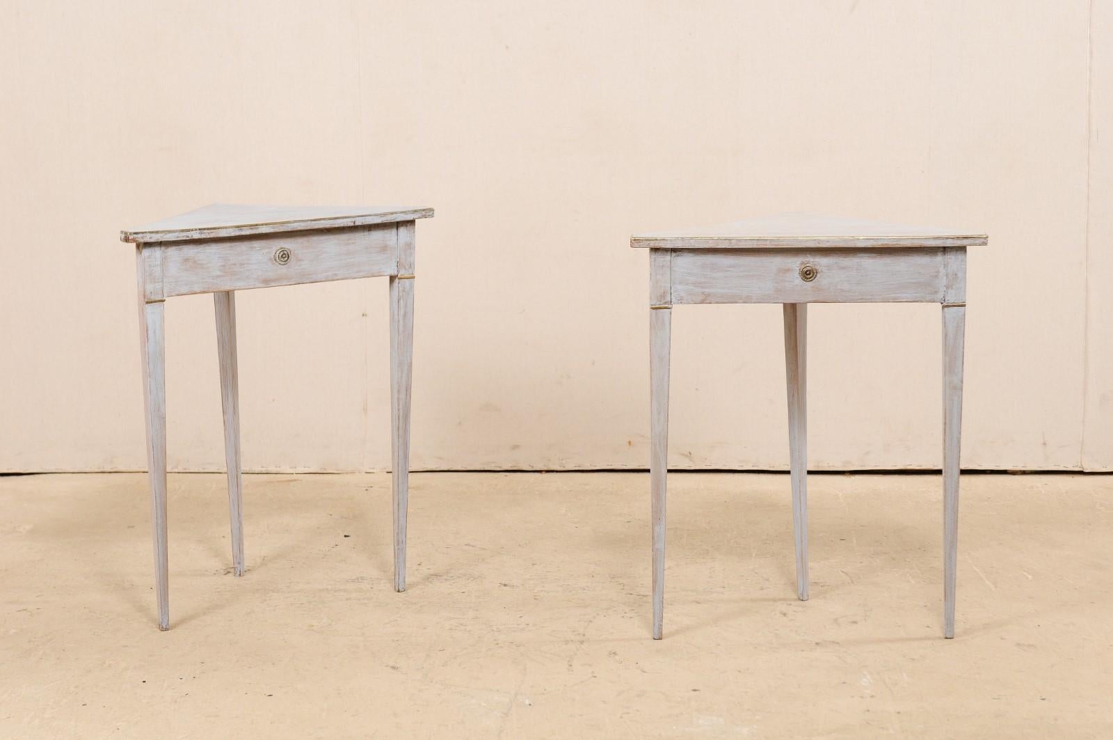 A pair of Swedish painted wooden corner tables from the 19th century. This pair of antique tables from Sweden each have triangular-shaped tops allowing them to be easily used in a corner space. The aprons are nice and clean, each adorned at its