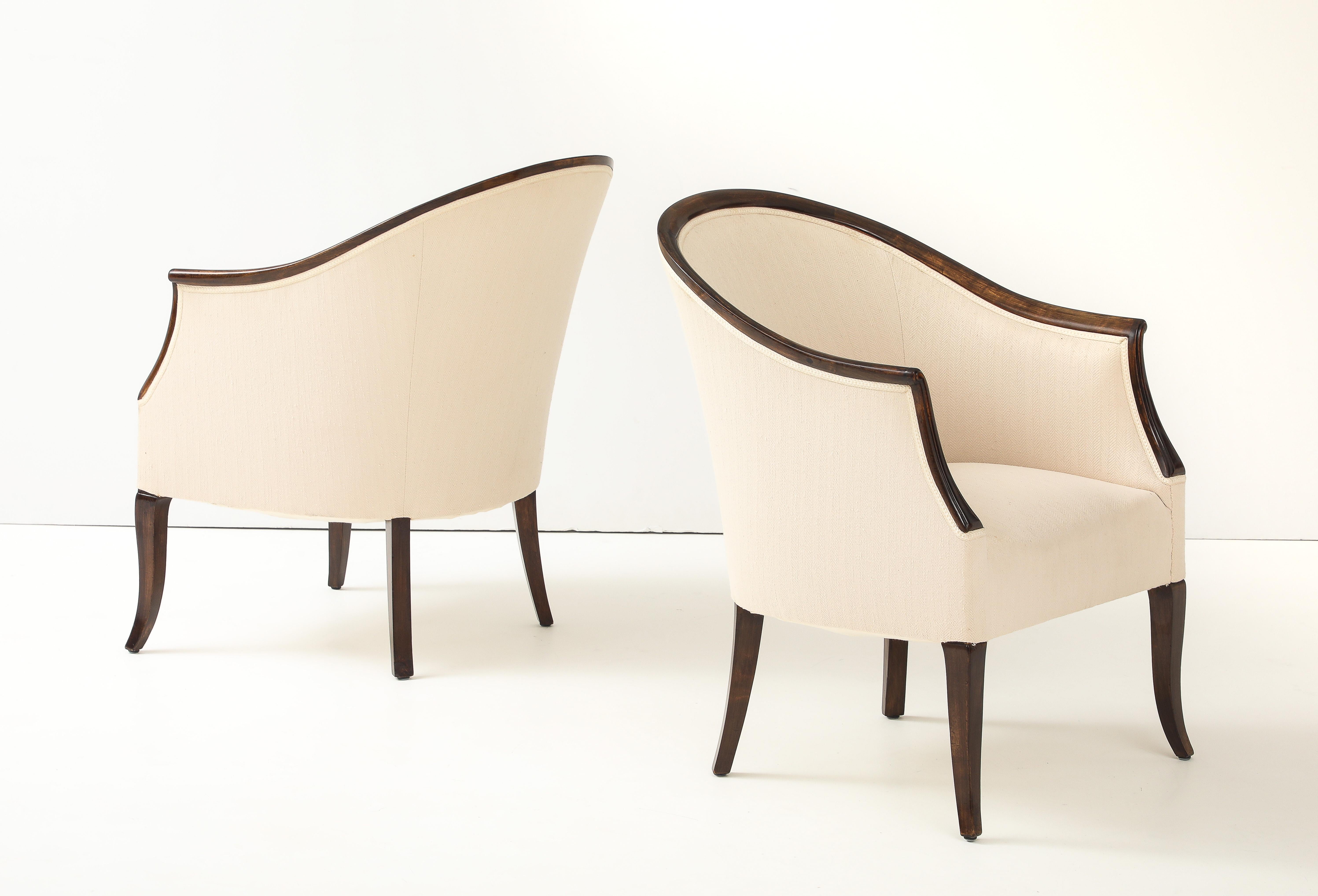 Paire de fauteuils suédois en bouleau teinté, vers les années 1940, chacun avec un généreux dossier incurvé, des supports d'accoudoir à volutes, un dossier et une assise bien rembourrés, le tout reposant sur des pieds fuselés et courbés.