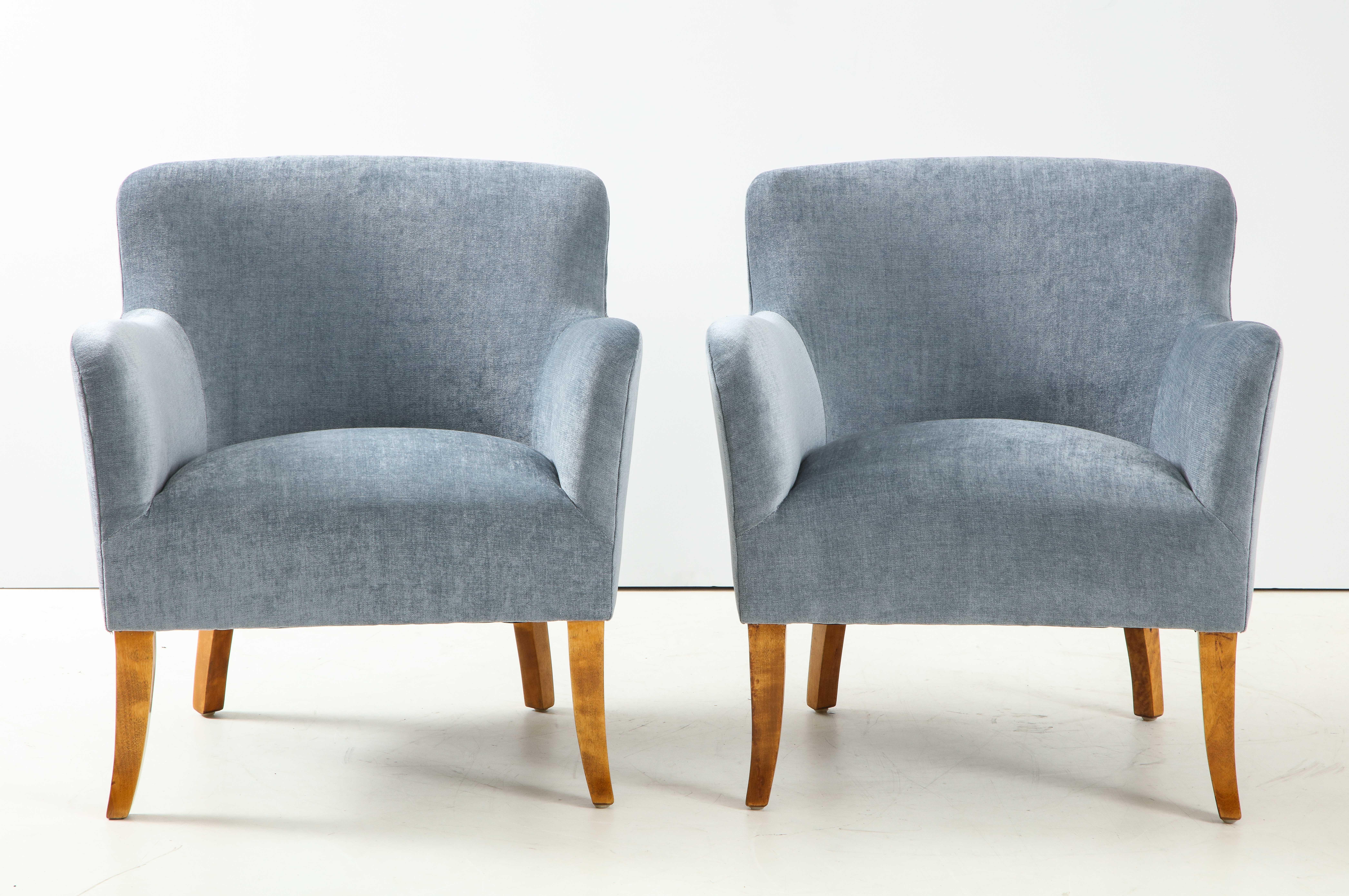 A pair of Swedish upholstered club chairs, circa 1940s, with rectangular and curved back, tight seat and curved armrests raised on Birchwood outplayed sabre legs.