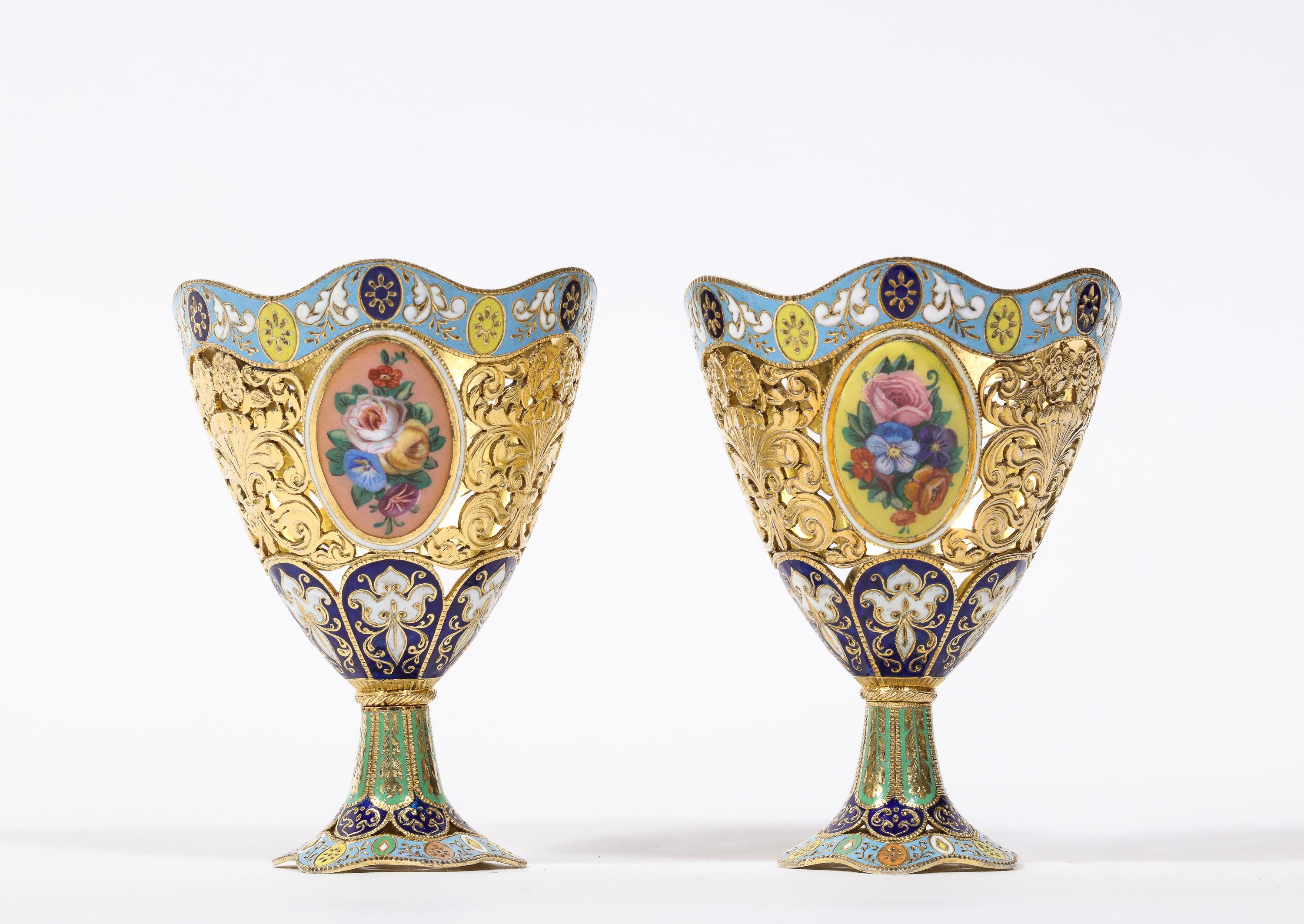 A pair of swiss gold and enamel Zarfs, Geneva, circa 1830, made for the Turkish Ottoman market.

Of vase form, the bodies pierced with foliate panels, alternating with oval enamel panels enclosing floral bouquets, the base and rim with enamel