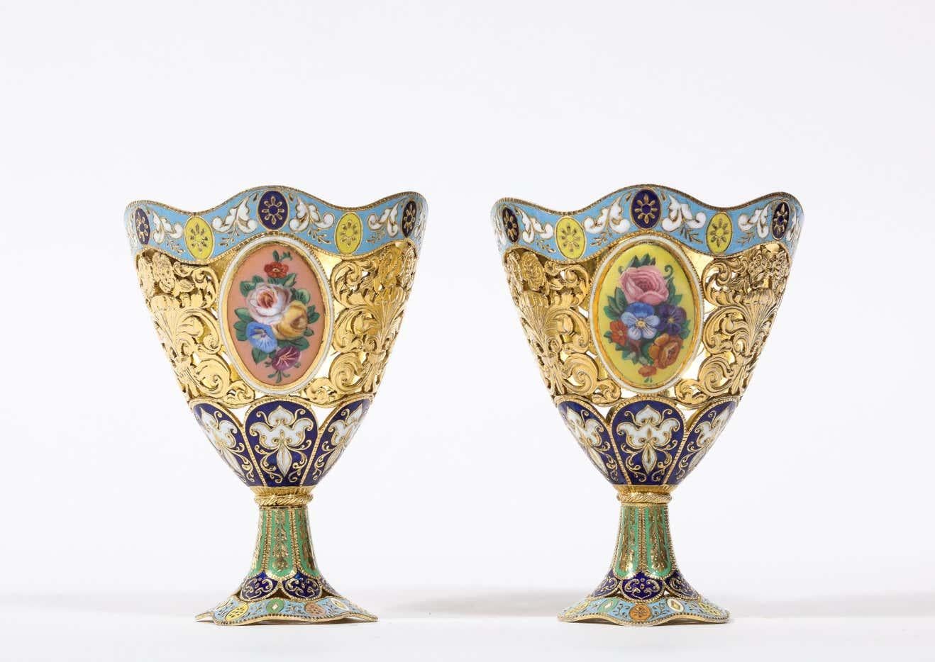 A Pair of Swiss Gold and Enamel Zarfs, Geneva, circa 1830, made for the Turkish Ottoman market.  

Of vase form, the bodies pierced with foliate panels, alternating with oval enamel panels enclosing floral bouquets, the base and rim with enamel