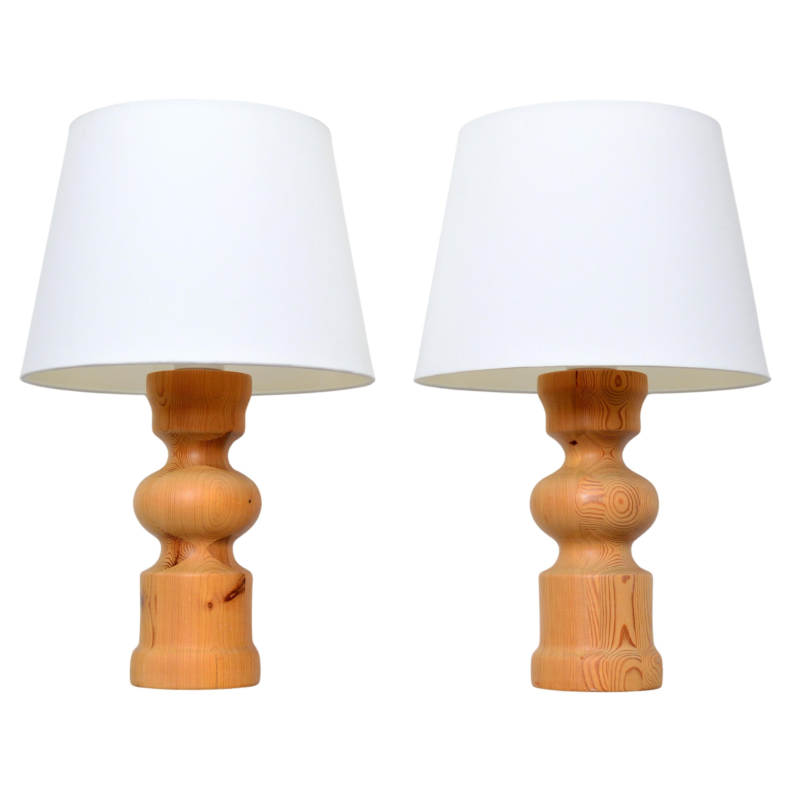 A pair of sculptural, solid pine table lamps made by Stilarmatur in Tranås Sweden. The  body of the design is turned pine wood. Although the form of the lamps is curvaceous and their edges soft, the scale of the lights and the proportions of the