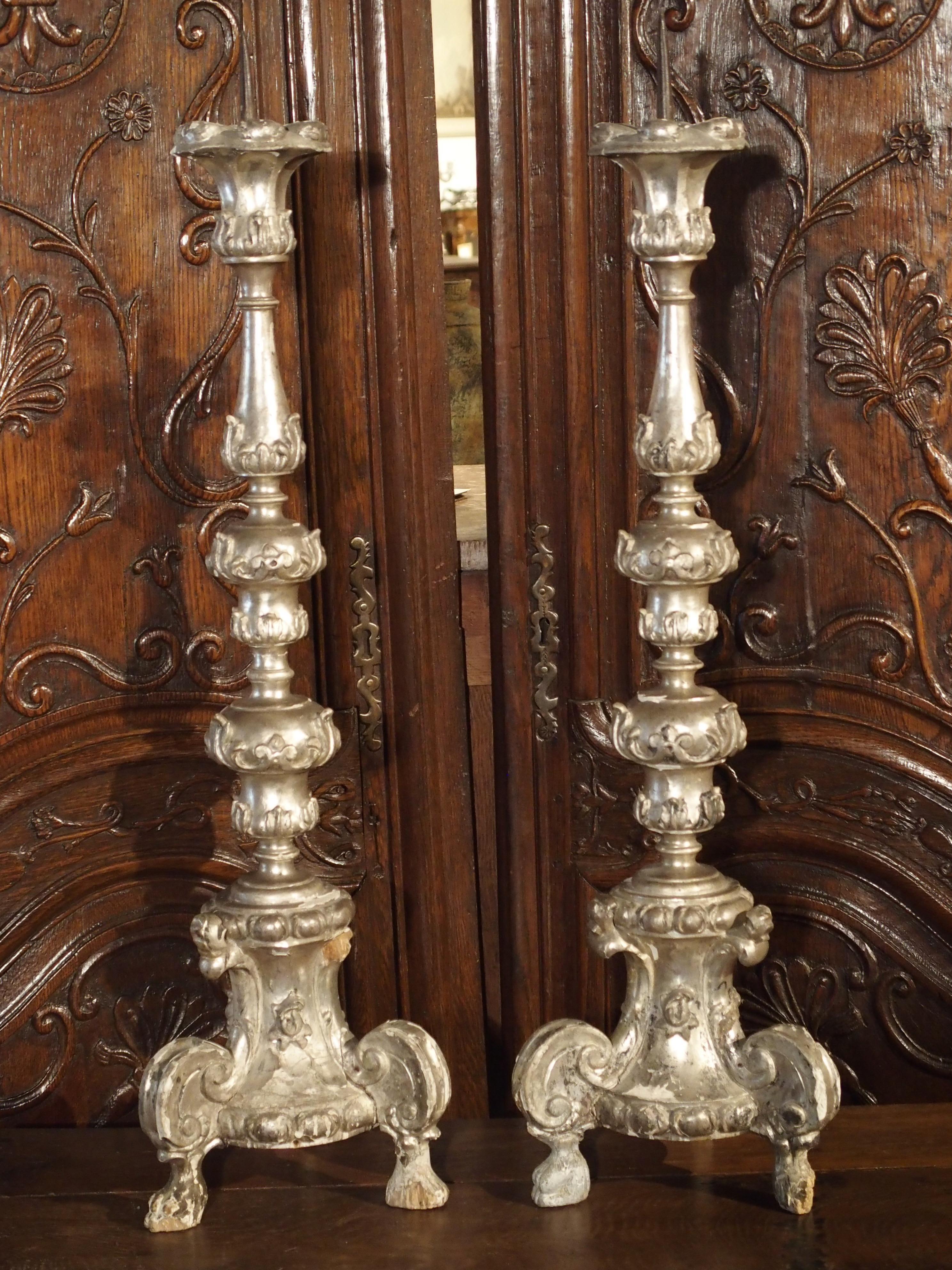 These tall silverleaf candlesticks date to the Baroque period of Italy, circa 1680.The tall shaped and turned stems all rest upon a tripod base with projecting c-scrolls and paw feet. The motifs are primarily varying forms of the acanthus leaf,