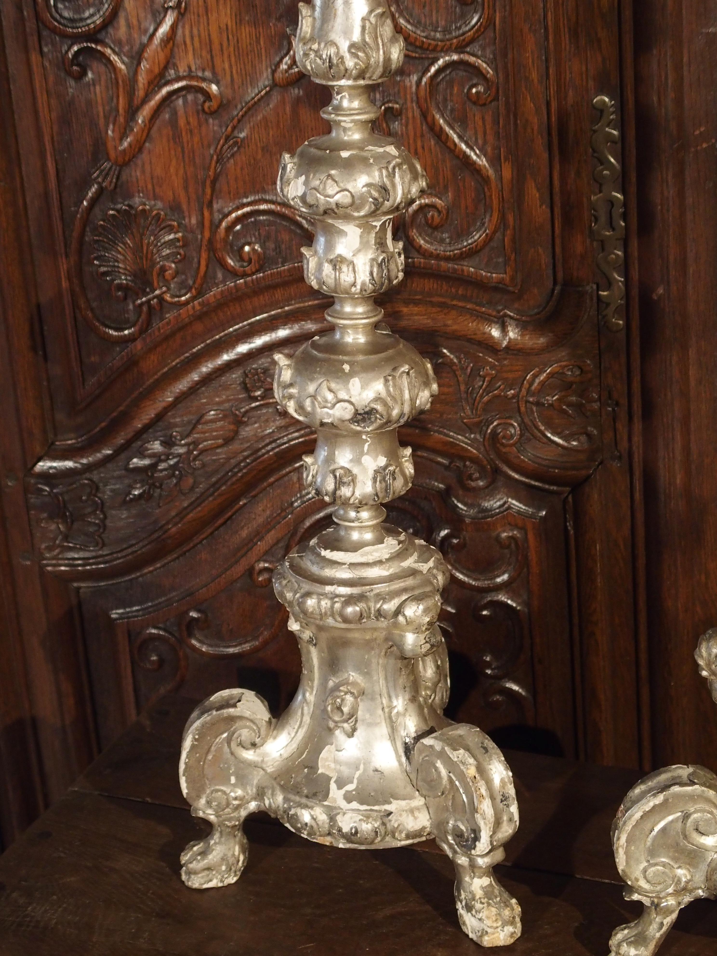 These tall silverleaf candlesticks date to the Baroque period of Italy, circa 1680.The tall shaped and turned stems all rest upon a tripod base with projecting C-scrolls and paw feet. The motifs are primarily varying forms of the acanthus leaf,