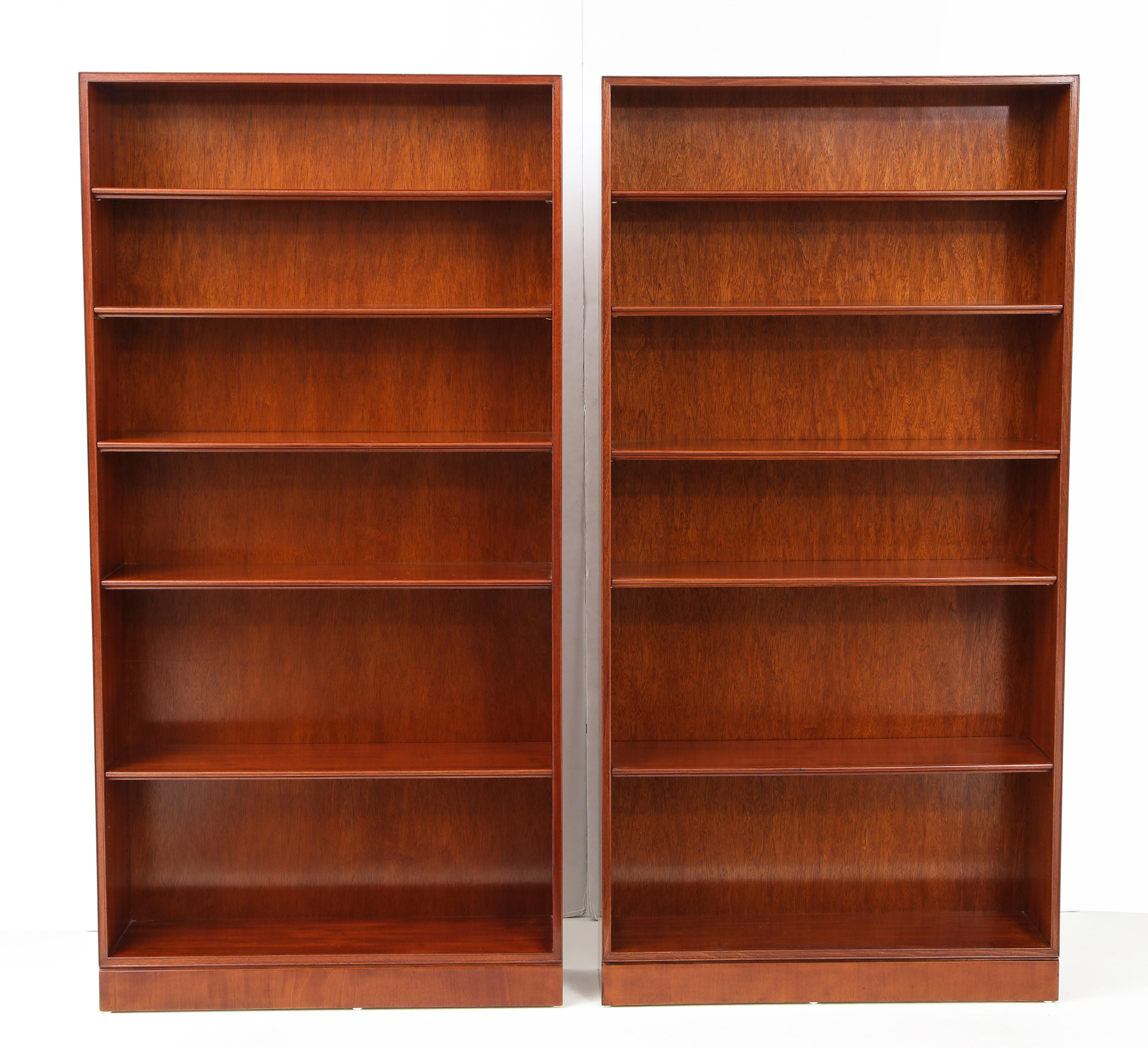 A pair of Danish mahogany tall open bookcases designed and produced by Frits Henningsen, circa 1940s, of clean rectangular form with a plinth base and each with five adjustable shelves with a molded front edge.