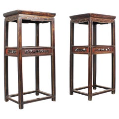 A pair of tall tables, stools, or pedestals crafted from carved and polychromed