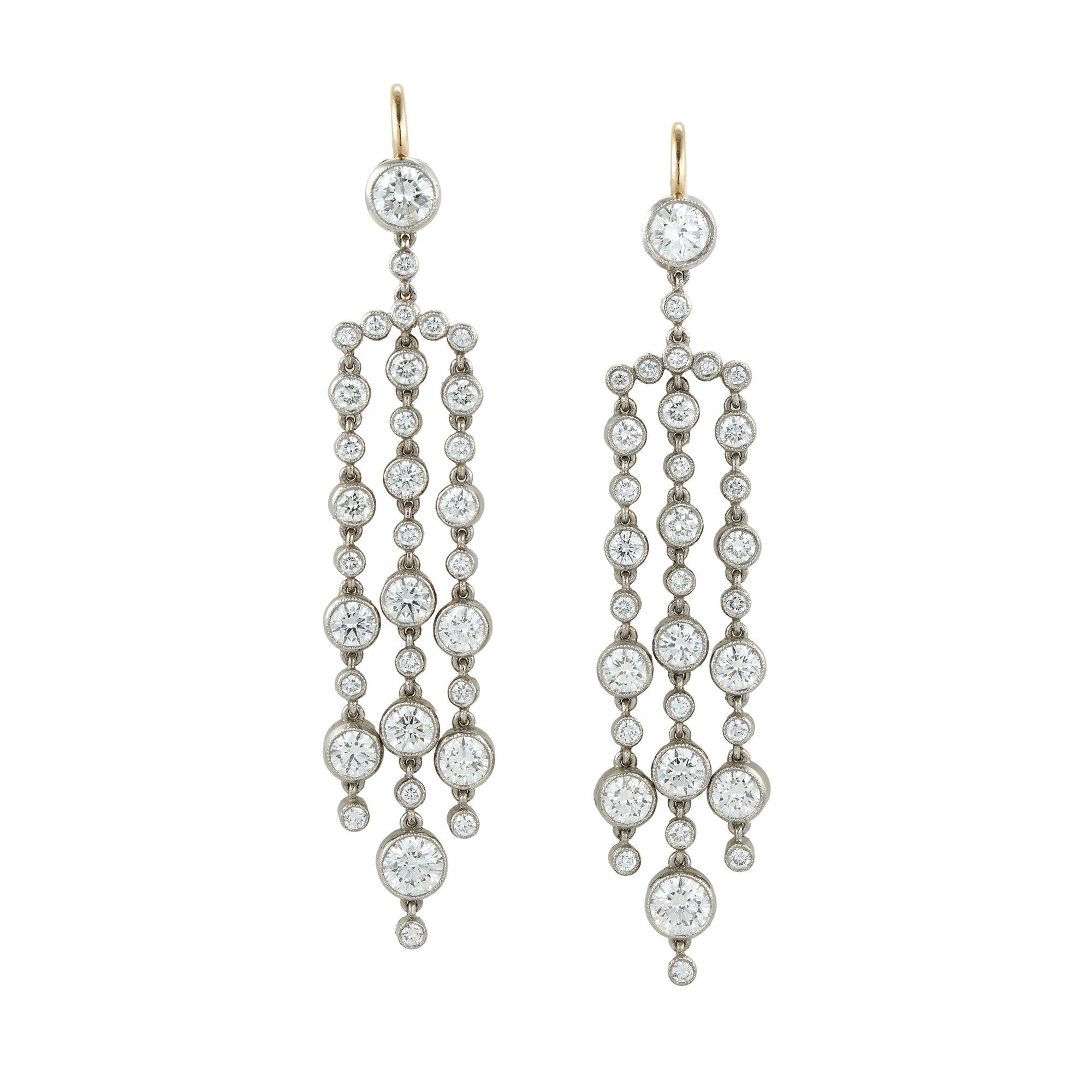 A pair of tassel diamond drop earrings, each earring comprising three graduating round brilliant-cut diamond-set tassels suspended from a curved bar with five diamonds surmounted from a round brilliant-cut diamond top, all diamonds weighing