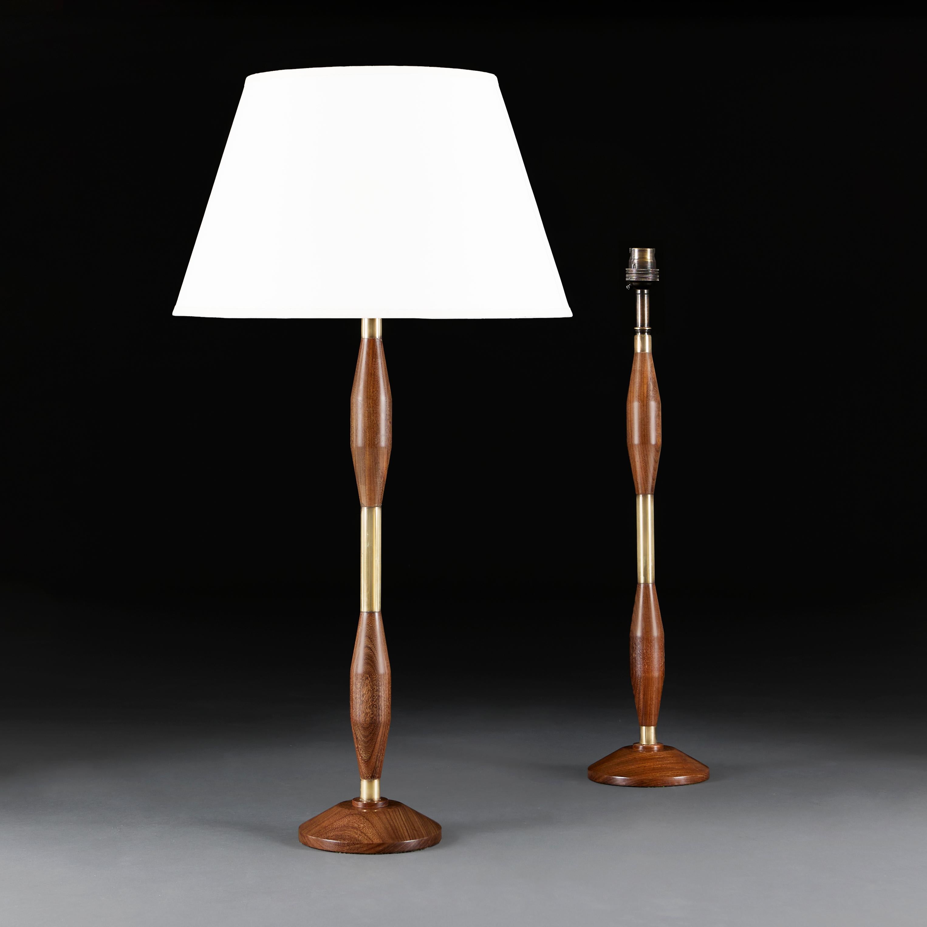 A pair of mid century teak and brass lamps, of torpedo form, the mahogany interspersed with brass banding, supported on circular bases.

Height of column 63.00cm
Height with shade 88.00cm
Diameter of base 17.00cm

Please note:
Lampshades not