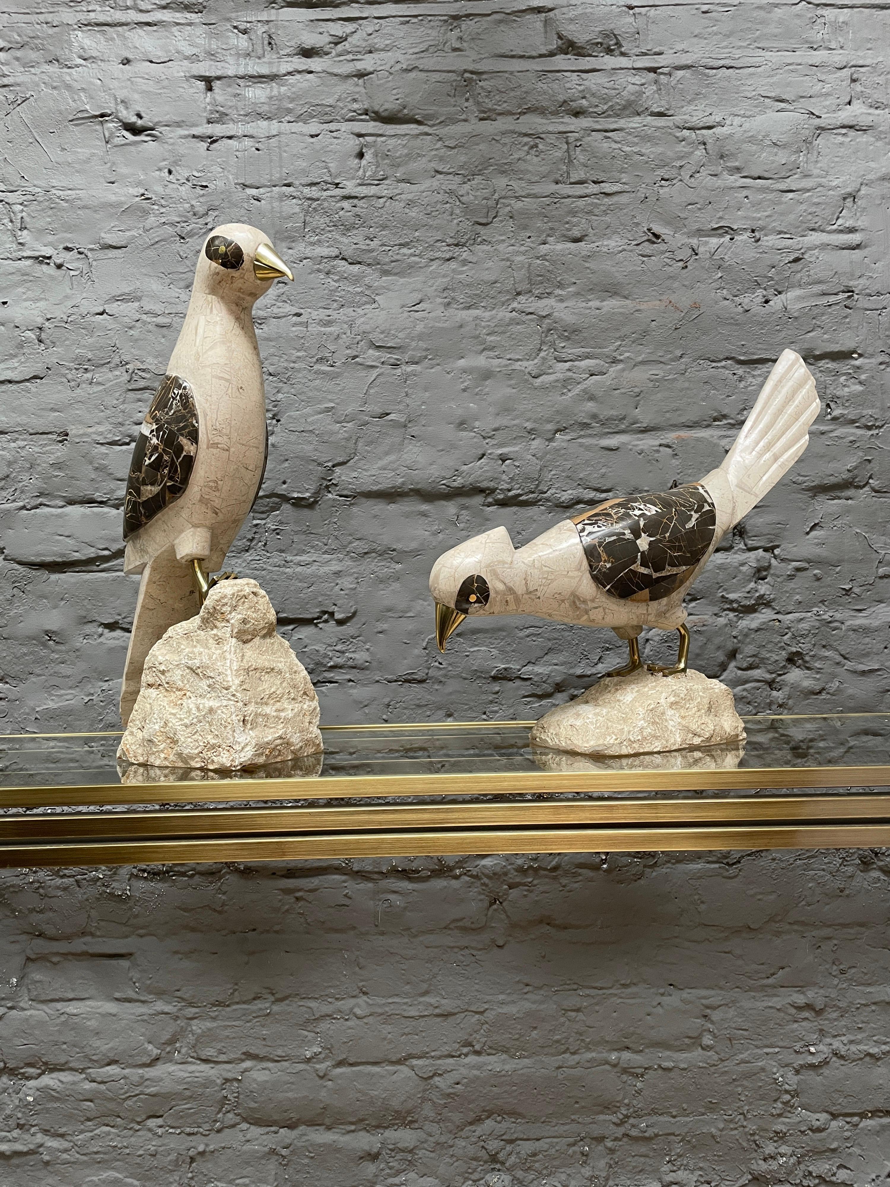 A pair of tessellated marble and stone birds with brass beaks and feet. Perched on stylised boulders and each one in a different pose. Made by Maitland Smith USA.