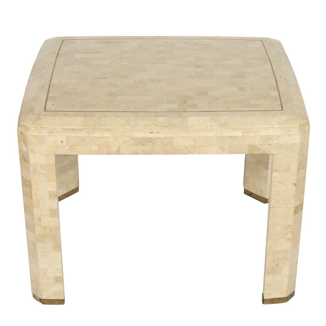 A pair of tessellated stone side tables with beveled edges in shades of white, cream and grey with brass trim.