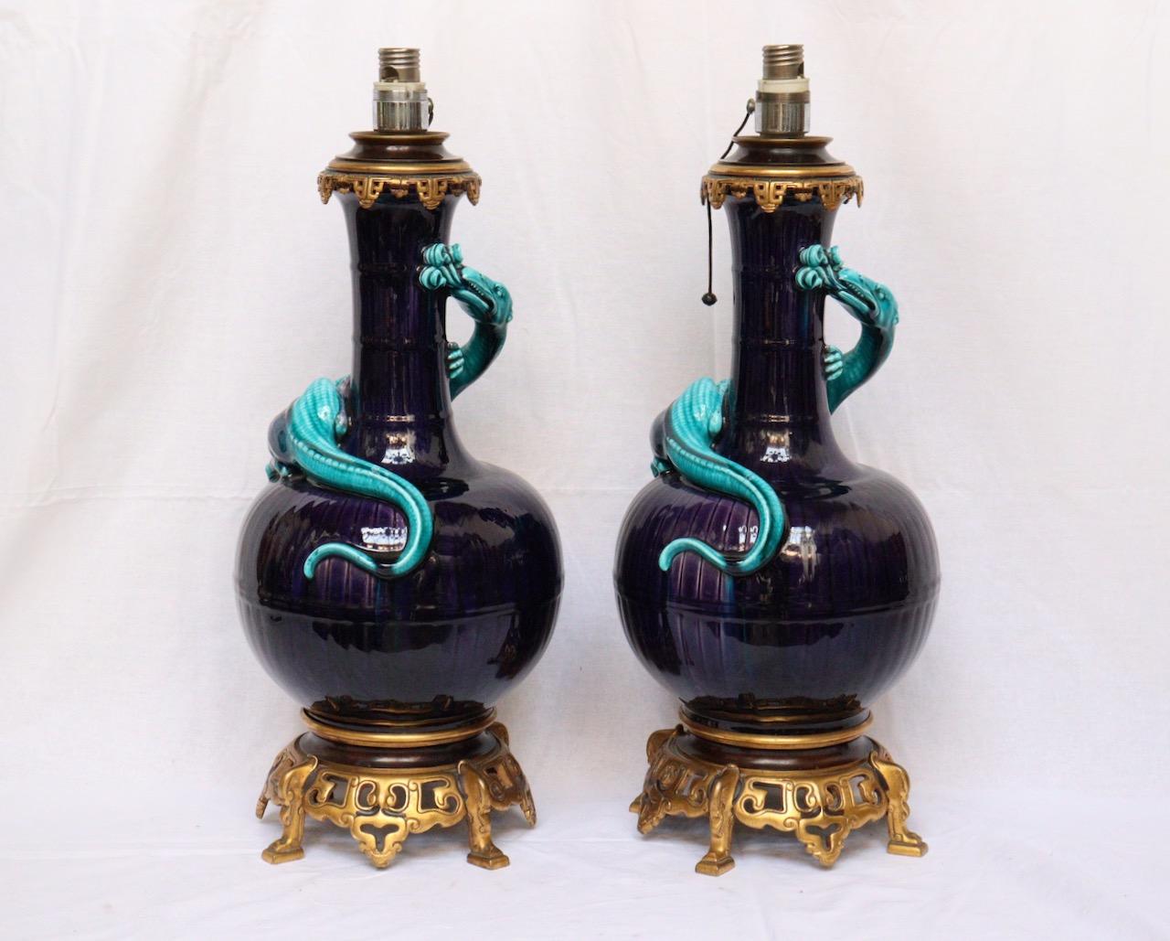 Théodore Deck (1823-1891)
A pair of Lizards vases ormolu-mounted in lamps
Enamelled Faïence vases with Aubergine background imitating basketry, Adorned with typically Blue Deck Salamanders. 
Top quality openwork gilt and aubergine patinated