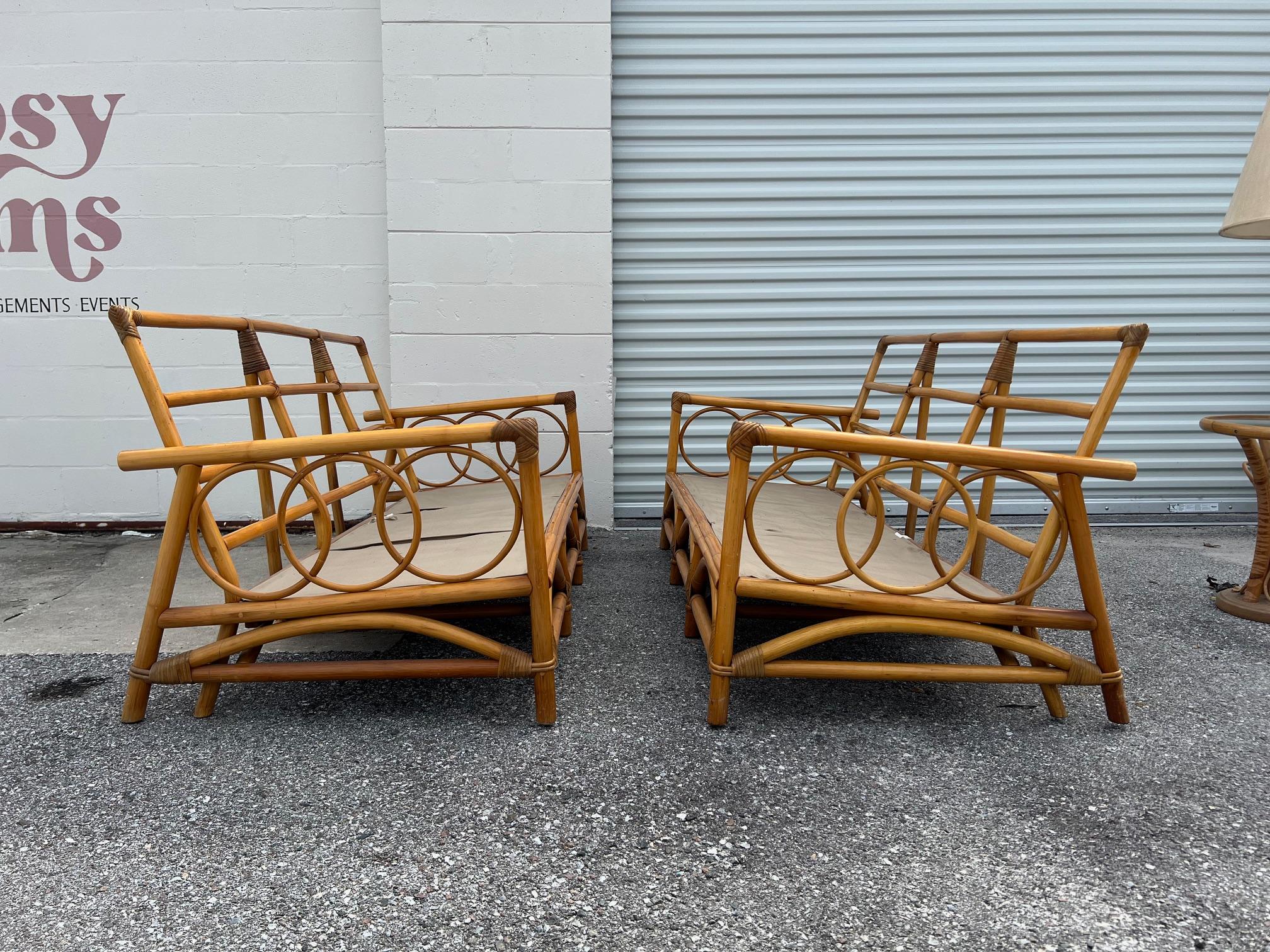 A pair of three seat rattan sofas with an interesting design. As a bonus-a side table with glass top and floor lamp are included. Sofas sold without cushions. Made by Herbach Rattan Furniture company.