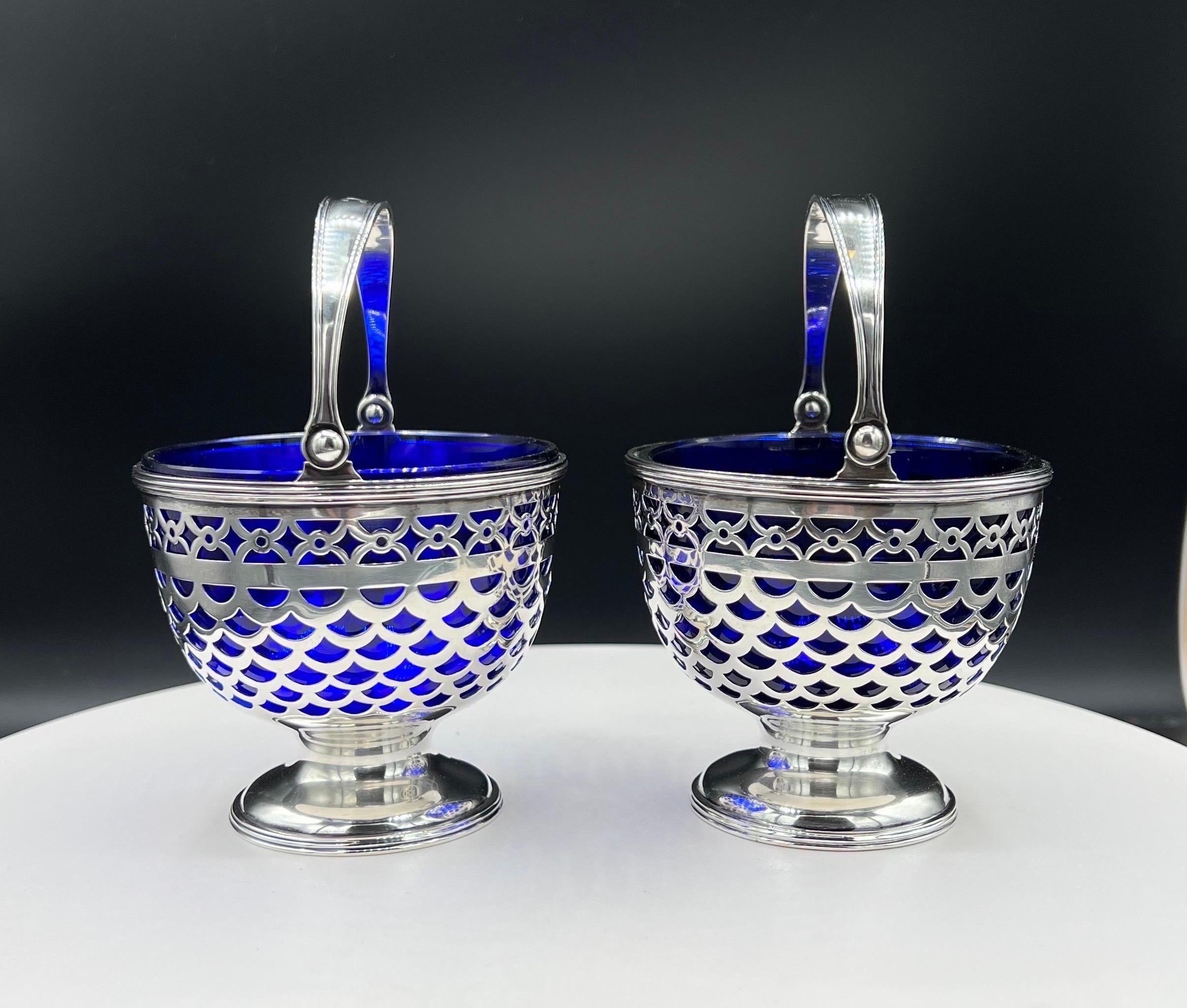 This sterling silver bonbon basket with a cobalt glass liner, by the world-renowned Tiffany & Company. It Pierced open-fret work design allows the cobalt glass to shine through. Raised on a pedestal base (not weighted) the basket handles Its fold