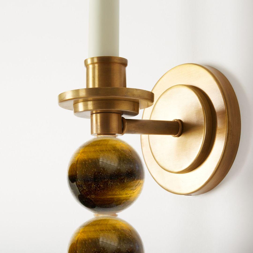 A pair of custom single-light Ephorus sconces with a circular backplate. Featuring a satin brass finish and Tiger’s Eye crystal orbs, this fixture can also be fabricated with glass balls, or with different artisan finish.

Sold as a pair but able to