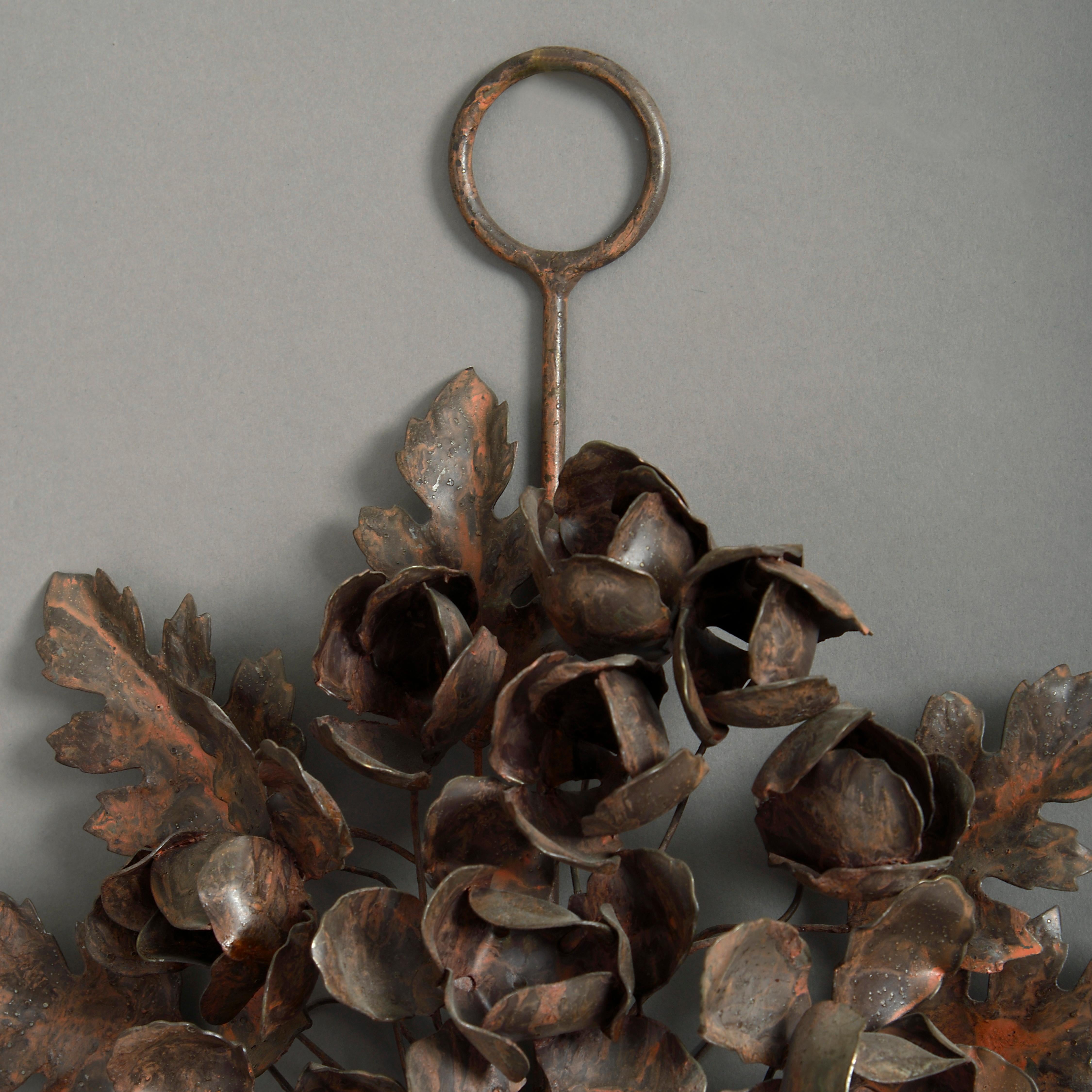 A pair of foliate tole wall lights, each generously applied with leaves, flower heads and a ribbon and having two scrolling candle arms.