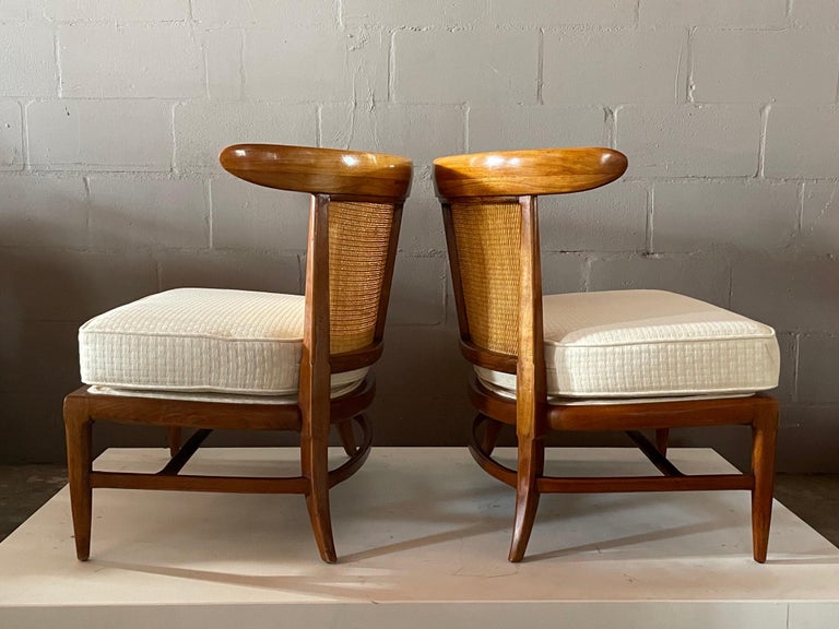 A pair of elegant Tomlinson lounge chairs. Caned back with loose seat cushion. Sculptural, wrap around back support.