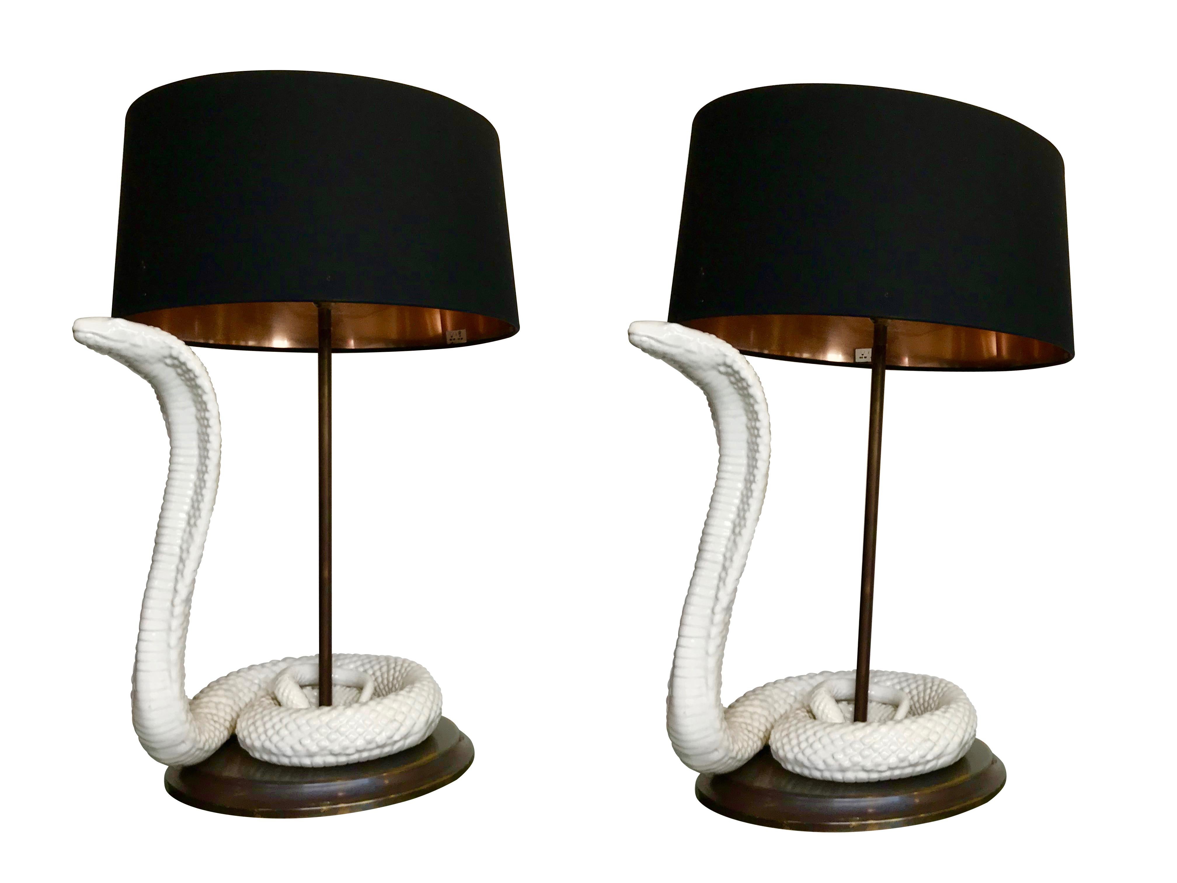 A pair of Tommaso Barbi lamps with white ceramic cobras on a brass base with new bespoke black and copper lined shades. Re wired with antique cord flex and PAT tested.