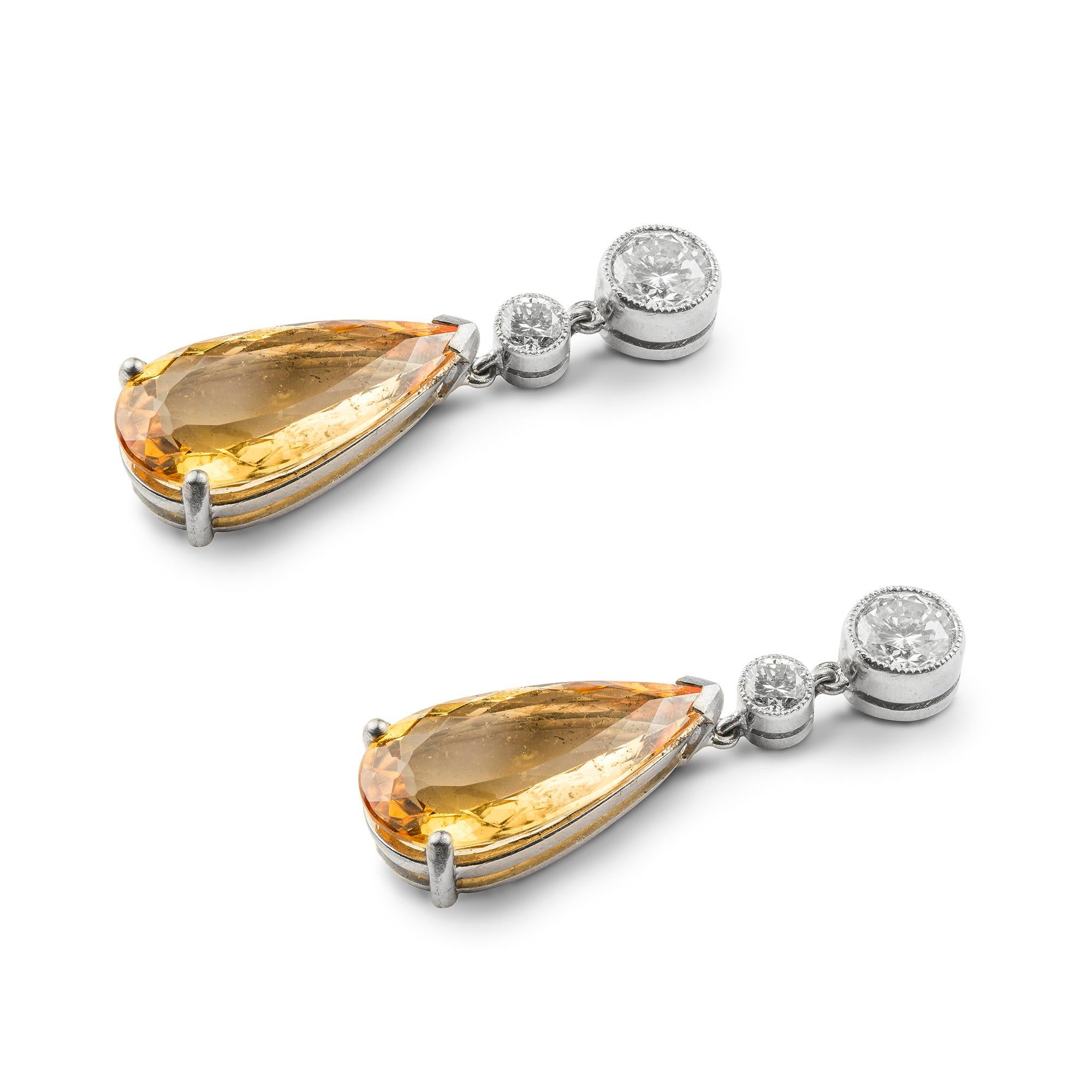 A pair of topaz and diamond drop earrings, the earrings consisting of two pear-shape topazes with total weight 9.40 carats, each suspended from two graduated round brilliant-cut diamonds with total weight of approximately one carat, millegrain-set
