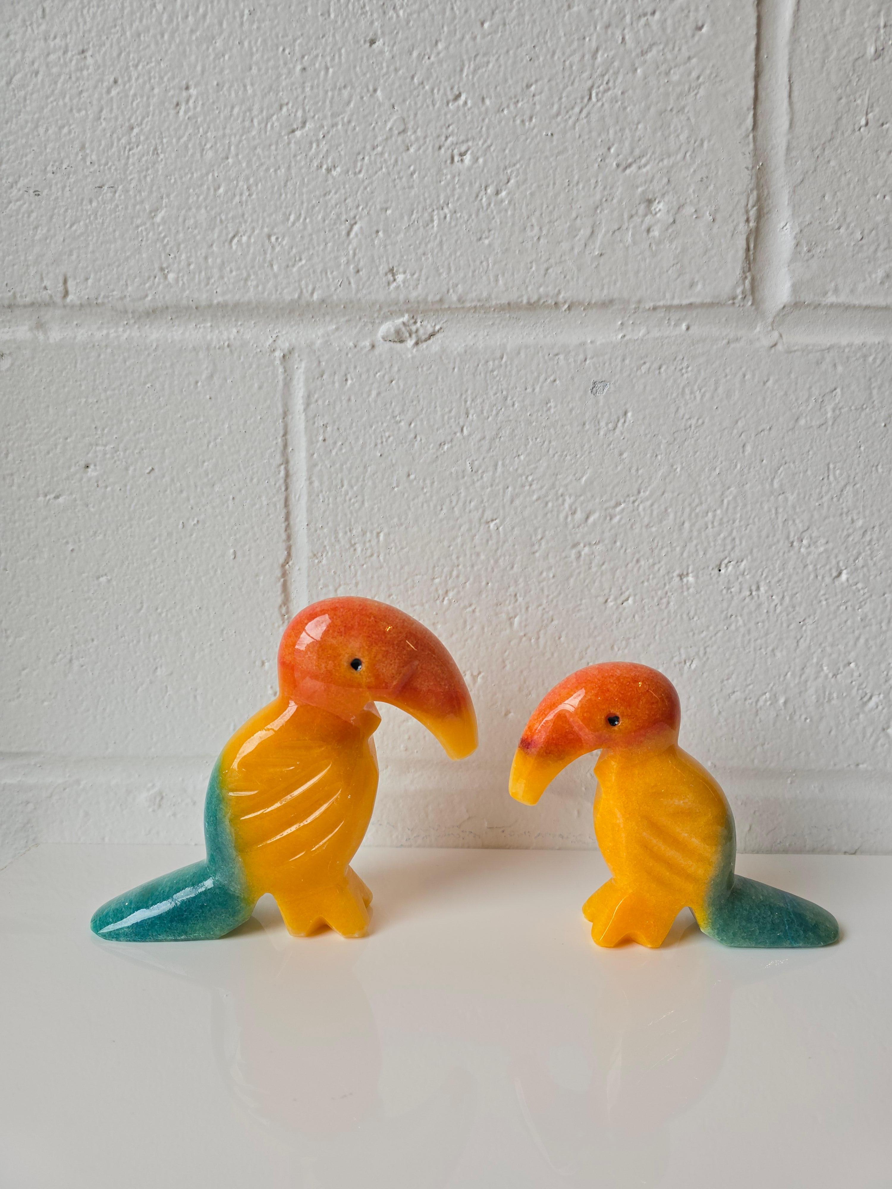Ein sorgfältig von Hand geschnitztes Paar Tukan- oder Pelikan-Vogelfiguren aus Onyx mit einer fesselnden Mischung aus orangefarbenen, gelben und grün-blauen Tönen.  Das Set enthält eine etwas größere und eine kleinere Figur, die sich ideal als