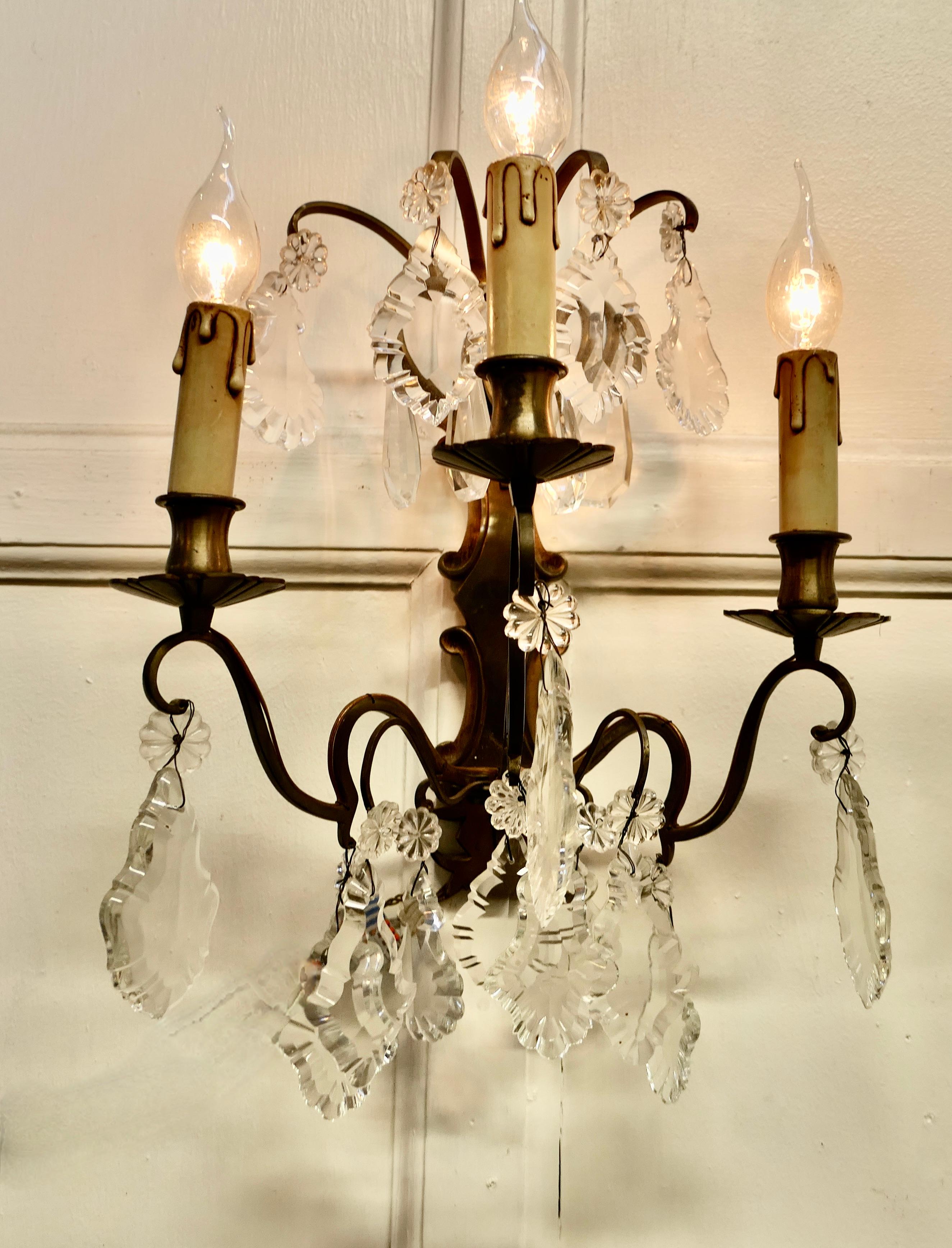A pair of triple wall chandeliers, two triple sconce wall lights.

These are very pretty wall lights, the cast brass sconces are hung with many large brightly cut pendants above and below which sparkle when electrified. 
The lights are all