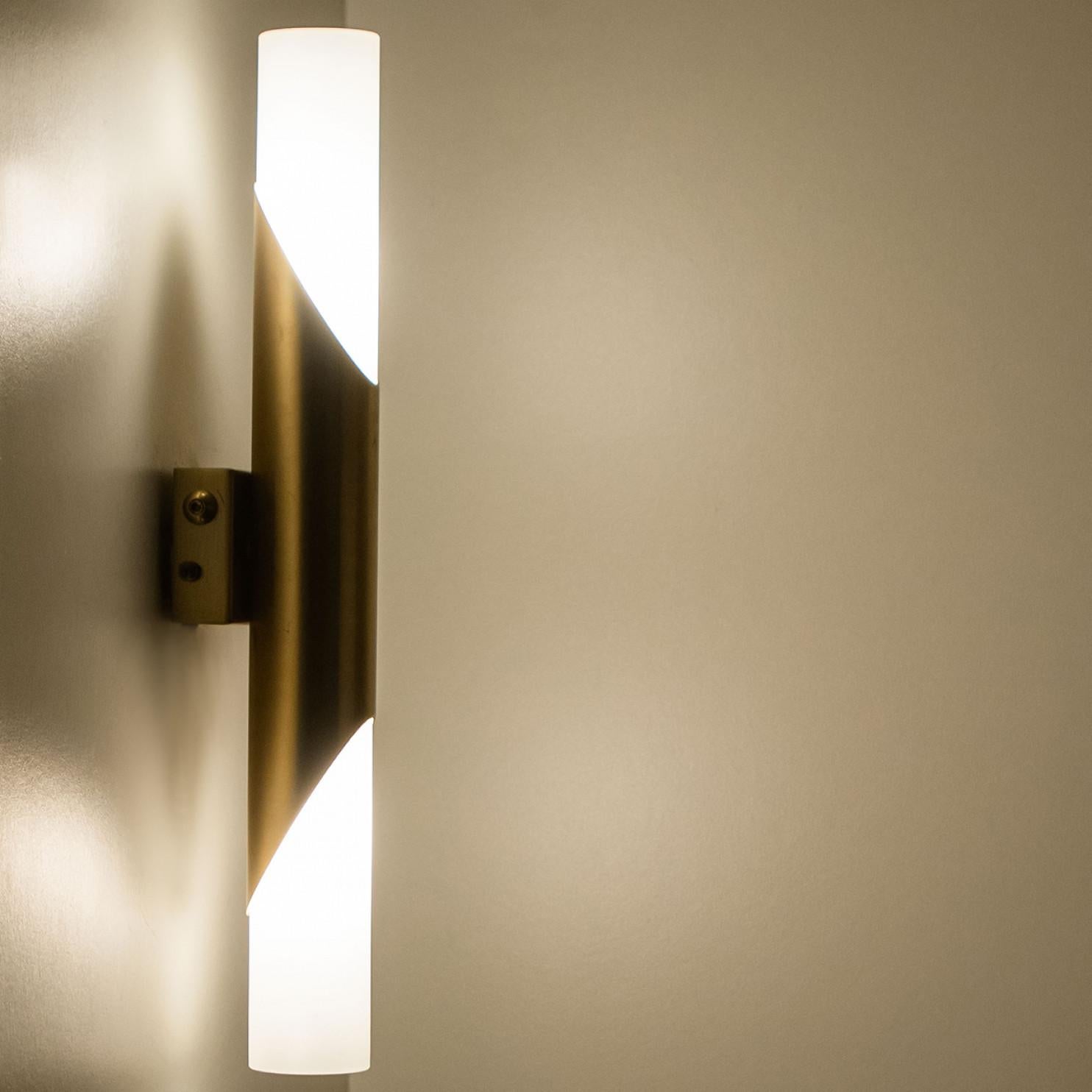 A minimalistic designed wall sconce, designed in Germany around 1970.
Each lamp is made of white milk glass with two bulb sockets on each end on a warm brass base.

Please note: the price is for the pair.

Dimensions:
Height: 15.74