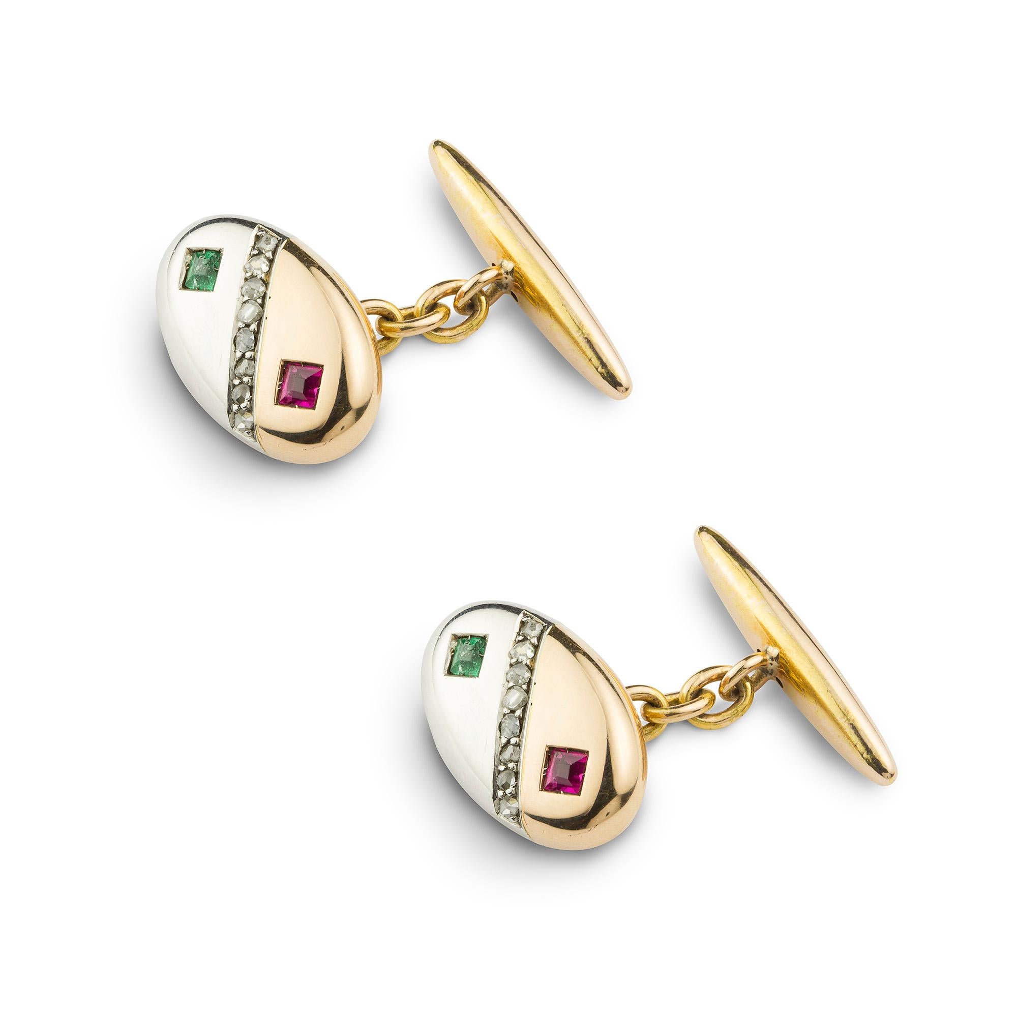 A pair of turn-of-the-century oval yellow and white gold gemset cufflinks, each cufflink comprising an oval plaque, set at a diagonal with yellow and white gold, separated with a stripe of rose-cut diamonds, the yellow gold section set to the centre