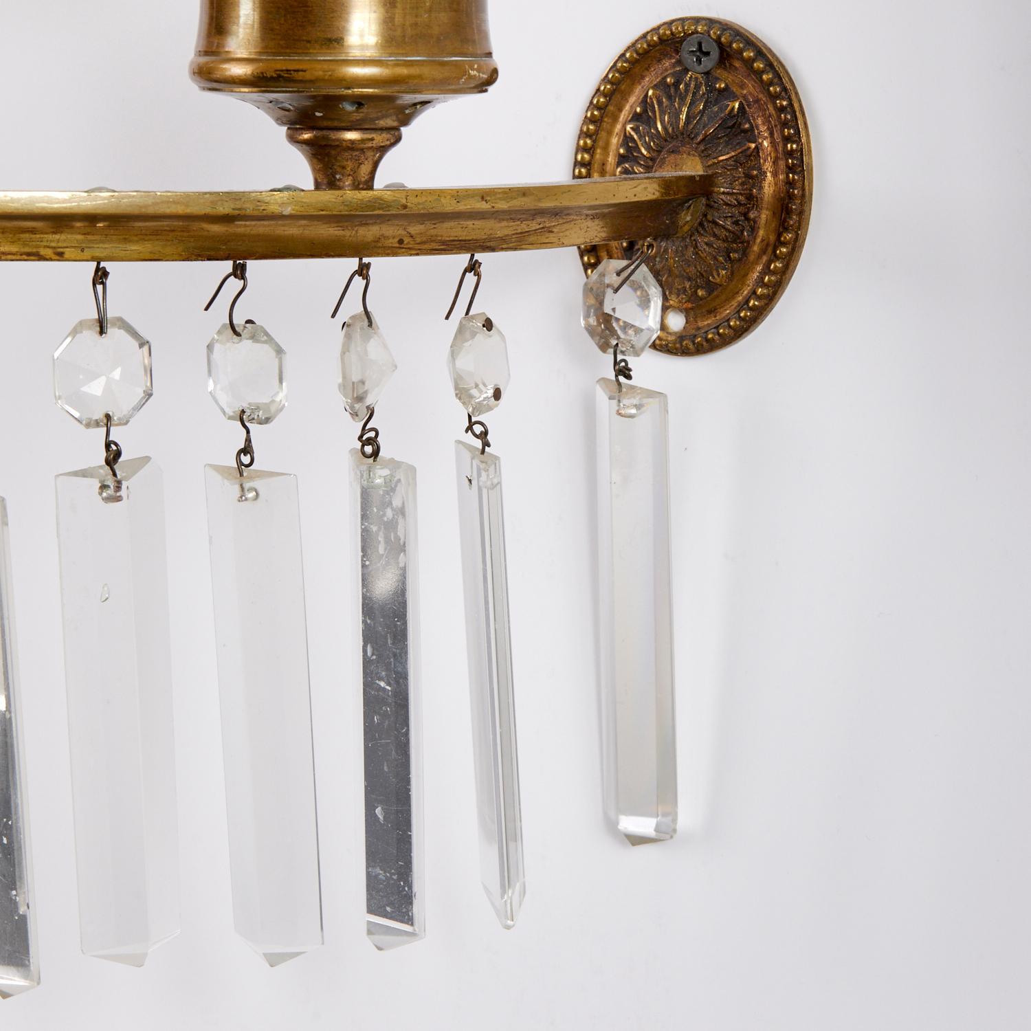 A pair of Regency-style two-light sconces with cut crystal ornaments. Circa 1900. 