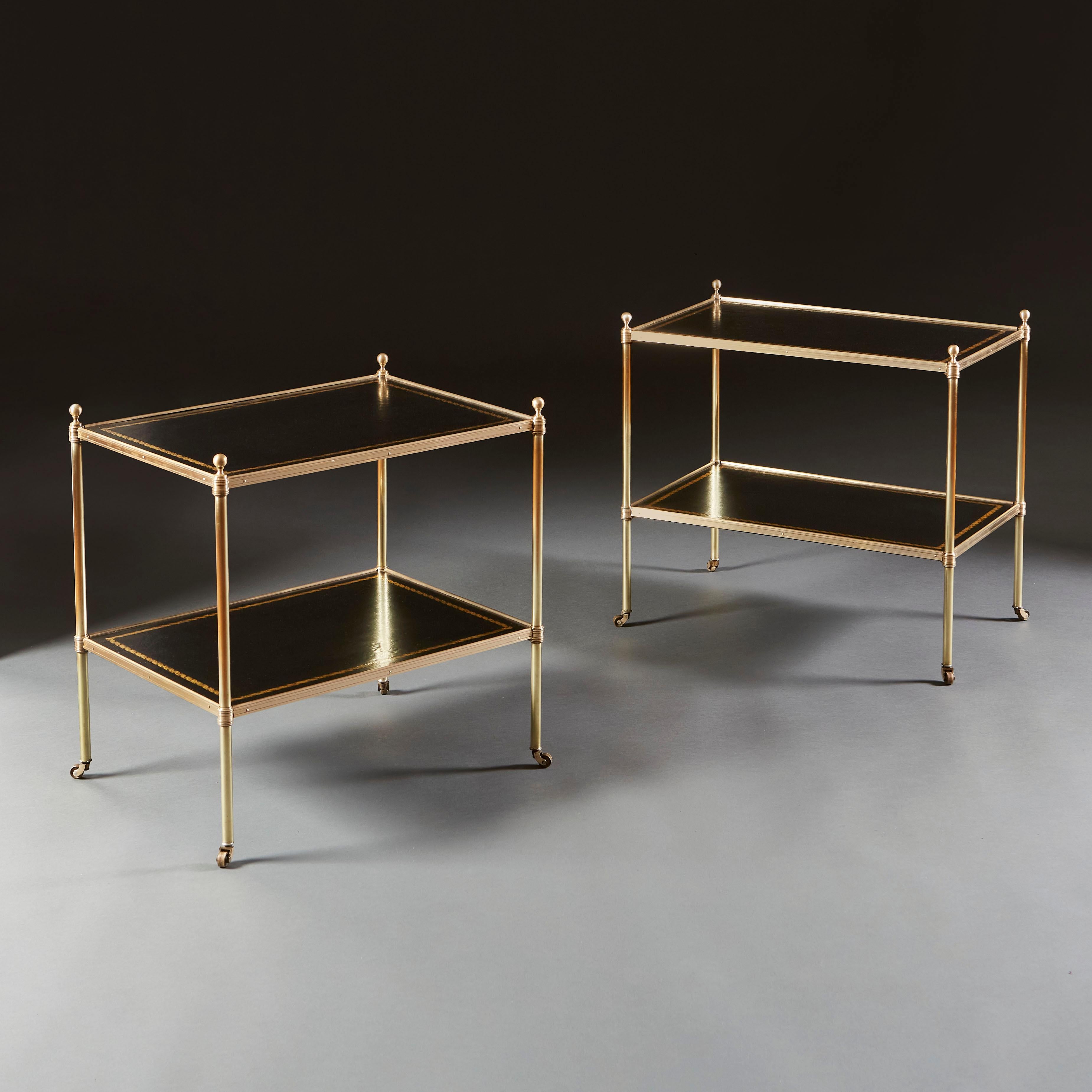 A pair of early twentieth century two tier etageres with black leather tops with gilt tooling. Of slightly differing size, please see dimensions below for measurements of each etagere.

Dimensions of smaller:
Height 55.00cm
Width 56.00cm
Depth